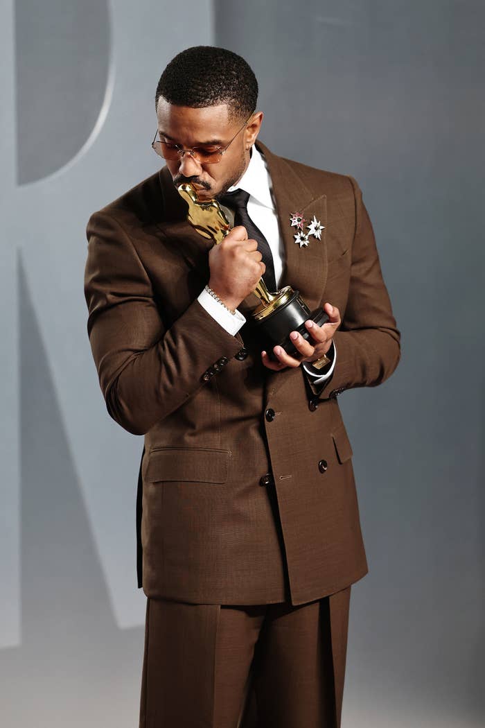 Person successful  a tailored suit   holds an award, gazing astatine  it