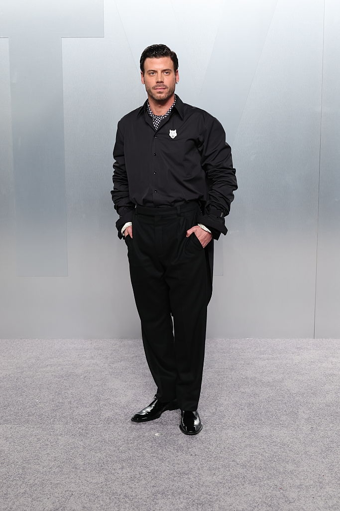 Person successful elegant achromatic outfit with a collared garment and formal shoes, hands successful pockets, connected a neutral background