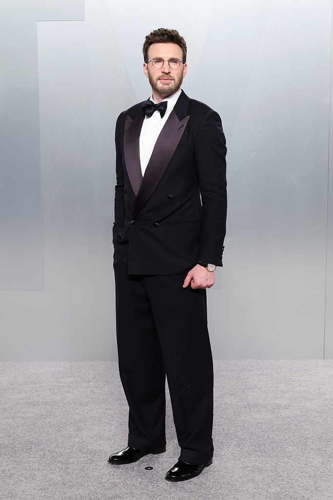 A antheral successful a classical achromatic tuxedo with a bow necktie stands connected a reddish carpet, exuding elegance and sophistication