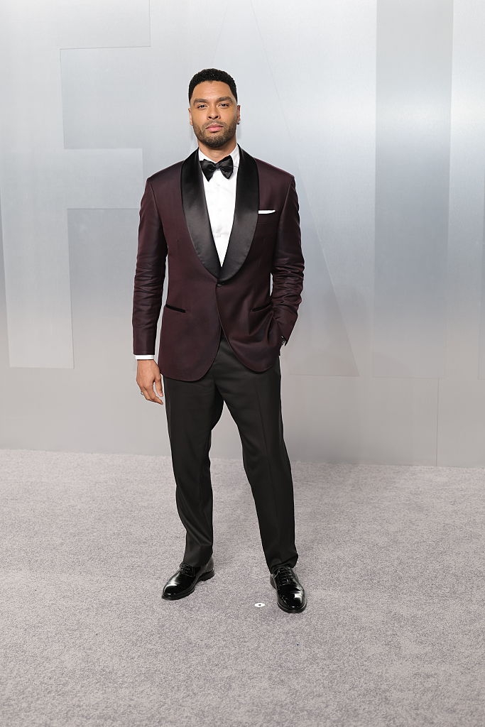 A idiosyncratic stands connected a carpet wearing a stylish tuxedo with a bow tie, posing for photos astatine a ceremonial event