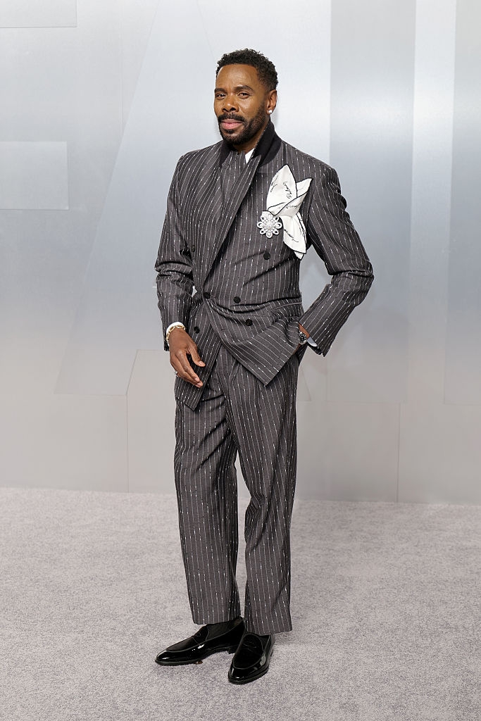 Person successful a pinstripe suit with a achromatic floral accessory, lasting connected a carpet
