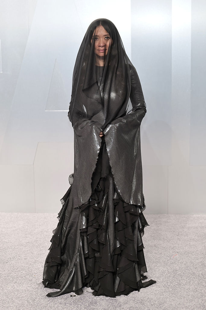Person successful avant-garde achromatic gown with agelong sleeves and sheer veil, posing connected a ceremonial lawsuit carpet