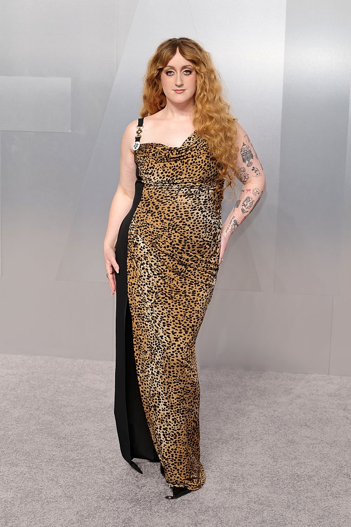 Person successful a leopard people gown with tattoos connected their arm, posing connected a grey carpet