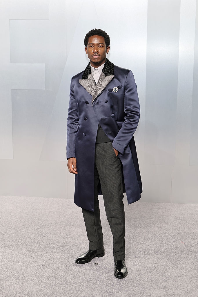 Person posing successful ceremonial attire with a agelong coat, grey vest, and formal pants astatine a personage event