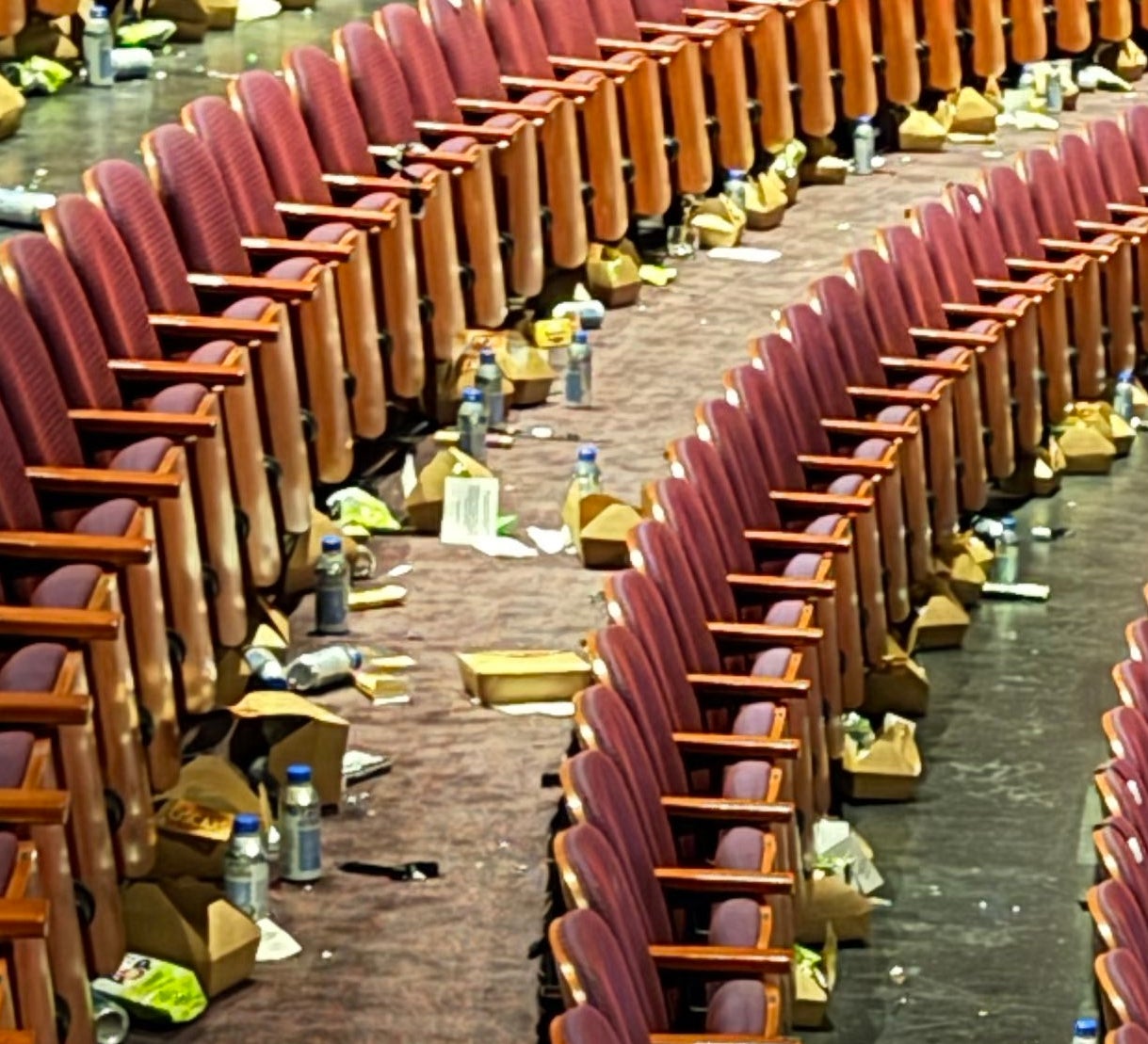 Empty theatre with rows of seats, scattered trash, and a fewer radical cleaning