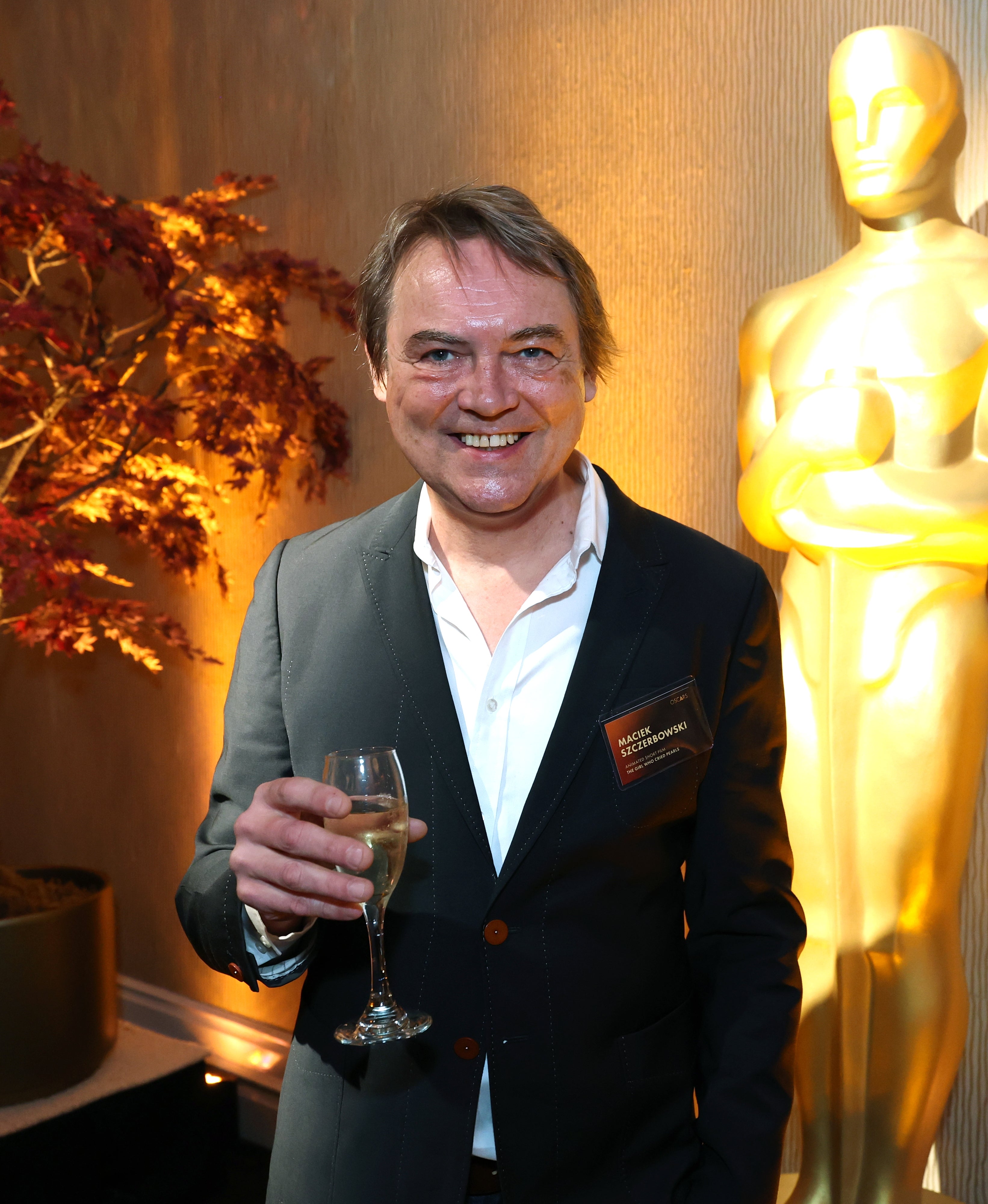 Person i dress som holder et vinglass, står ved siden av en gullstatue i en formell begivenhetssetting