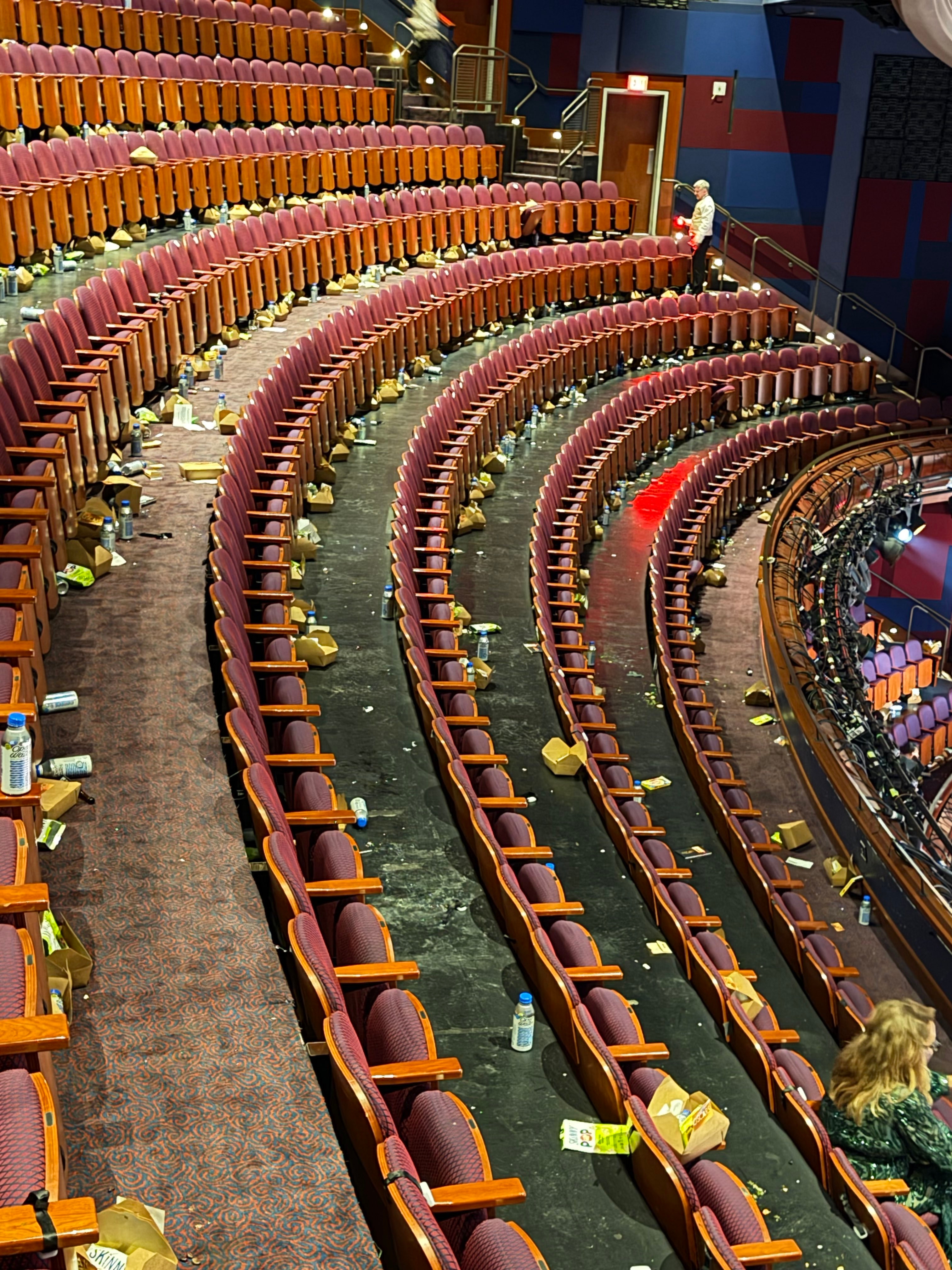 Empty theatre seats with scattered trash and nutrient containers near down by the audience
