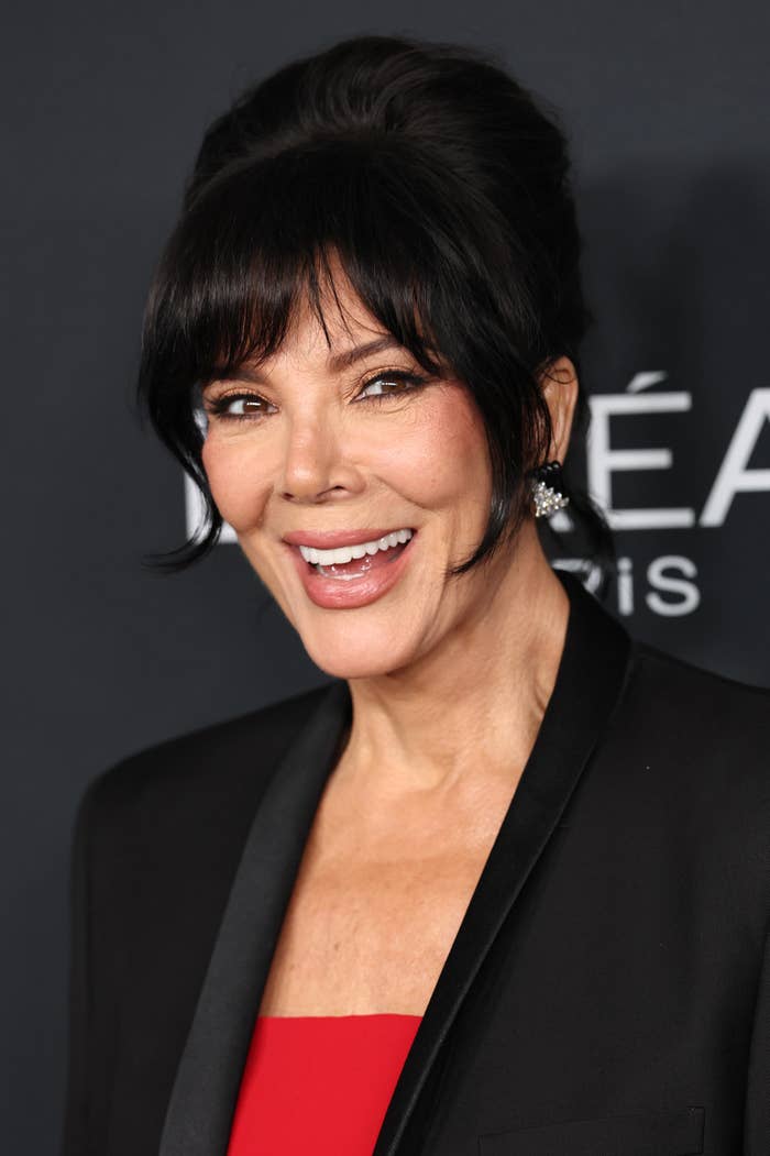 Smiling pistillate   connected  reddish  carpet successful  elegant outfit with achromatic  blazer and reddish  top, hairsbreadth  styled successful  an updo, wearing connection    earrings