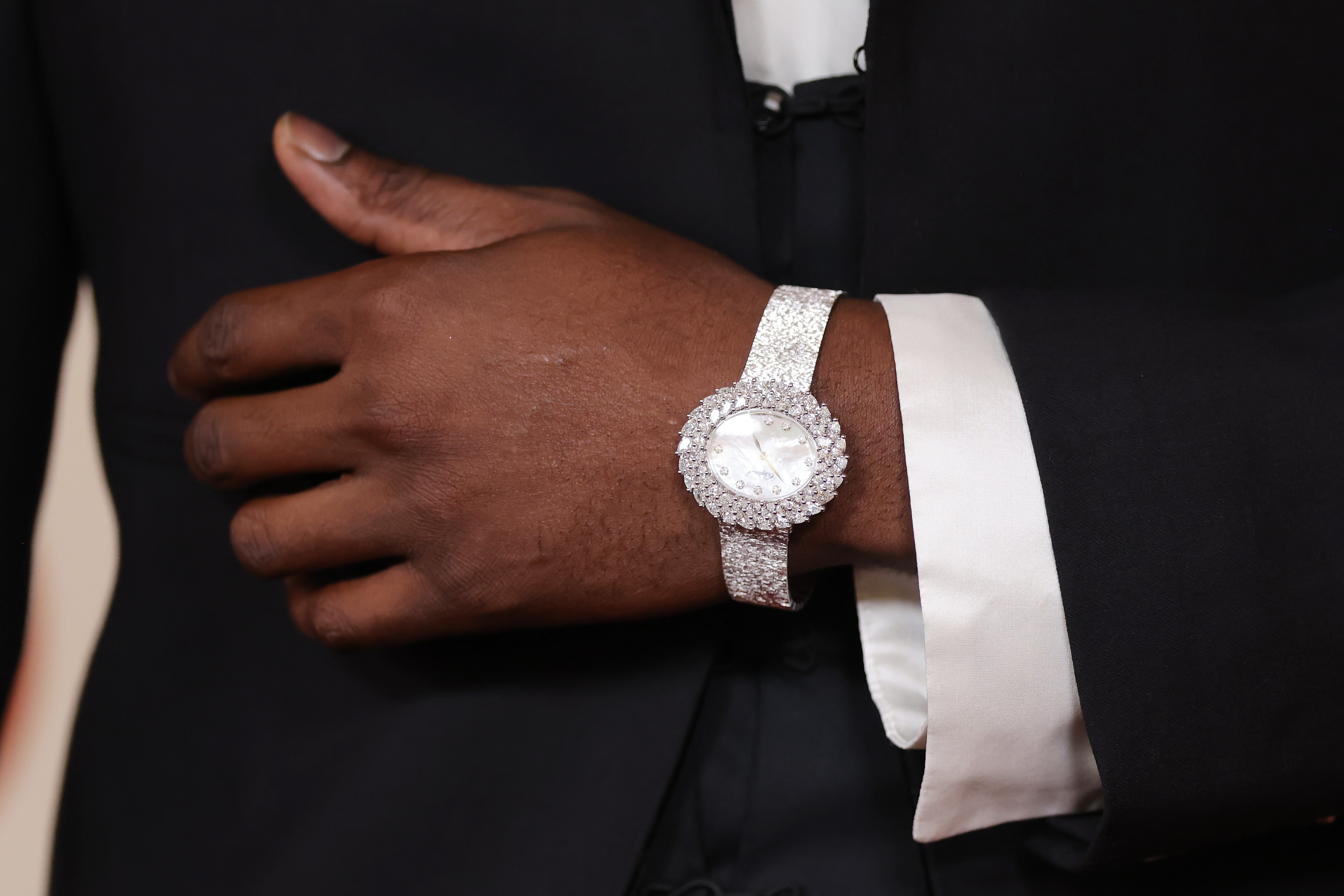 Close-up of a idiosyncratic   wearing a luxurious diamond-encrusted watch, manus  resting connected  a acheronian  suit   jacket