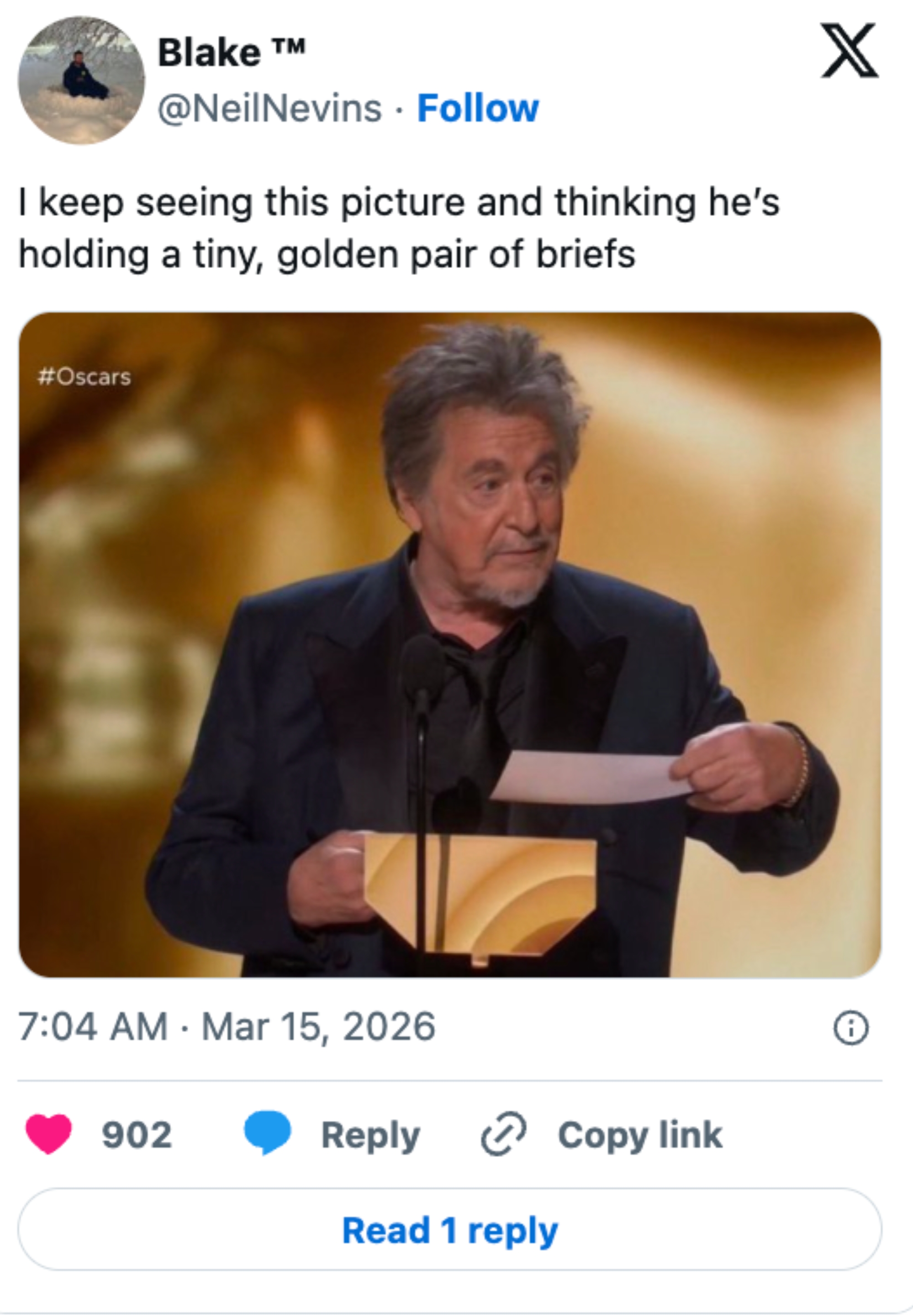 Man at Oscars podium holding an envelope, caption humorously suggests it looks like a tiny pair of briefs