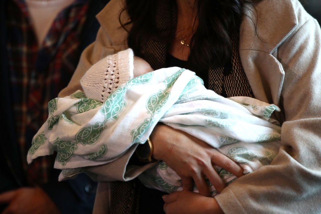 Person cradling a babe  successful  a patterned blanket, with the baby's caput  covered by a knit hat