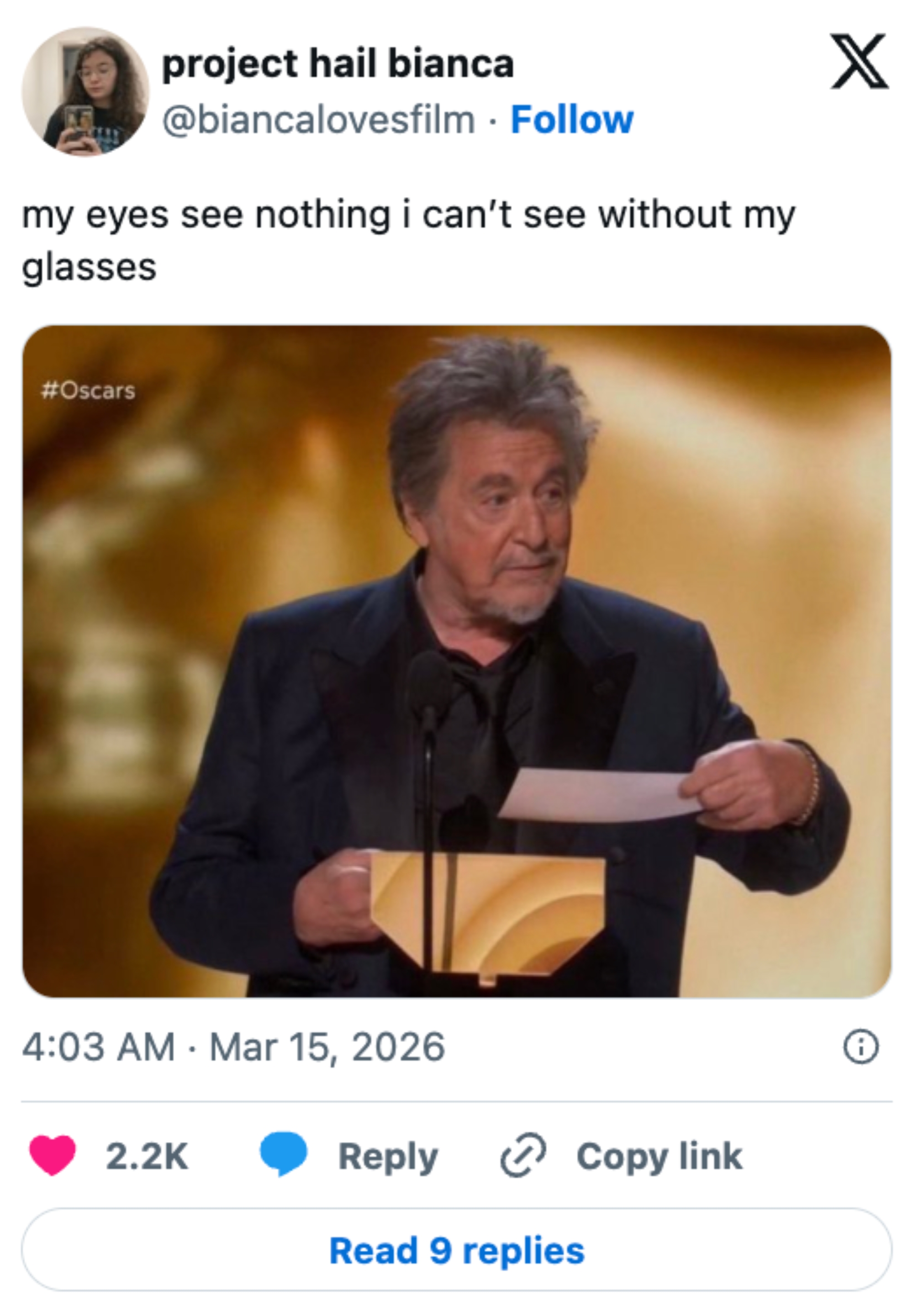 A person holding an envelope on stage at the Oscars, captioned with a humorous comment about needing glasses