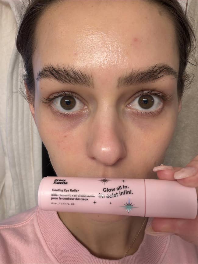 Person holding a pink cooling eye roller near their face, with the text 