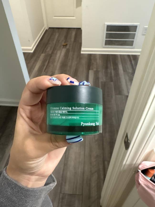 Person holding a jar of Pyunkang Yul Ultimate Calming Solution Cream with text in another language