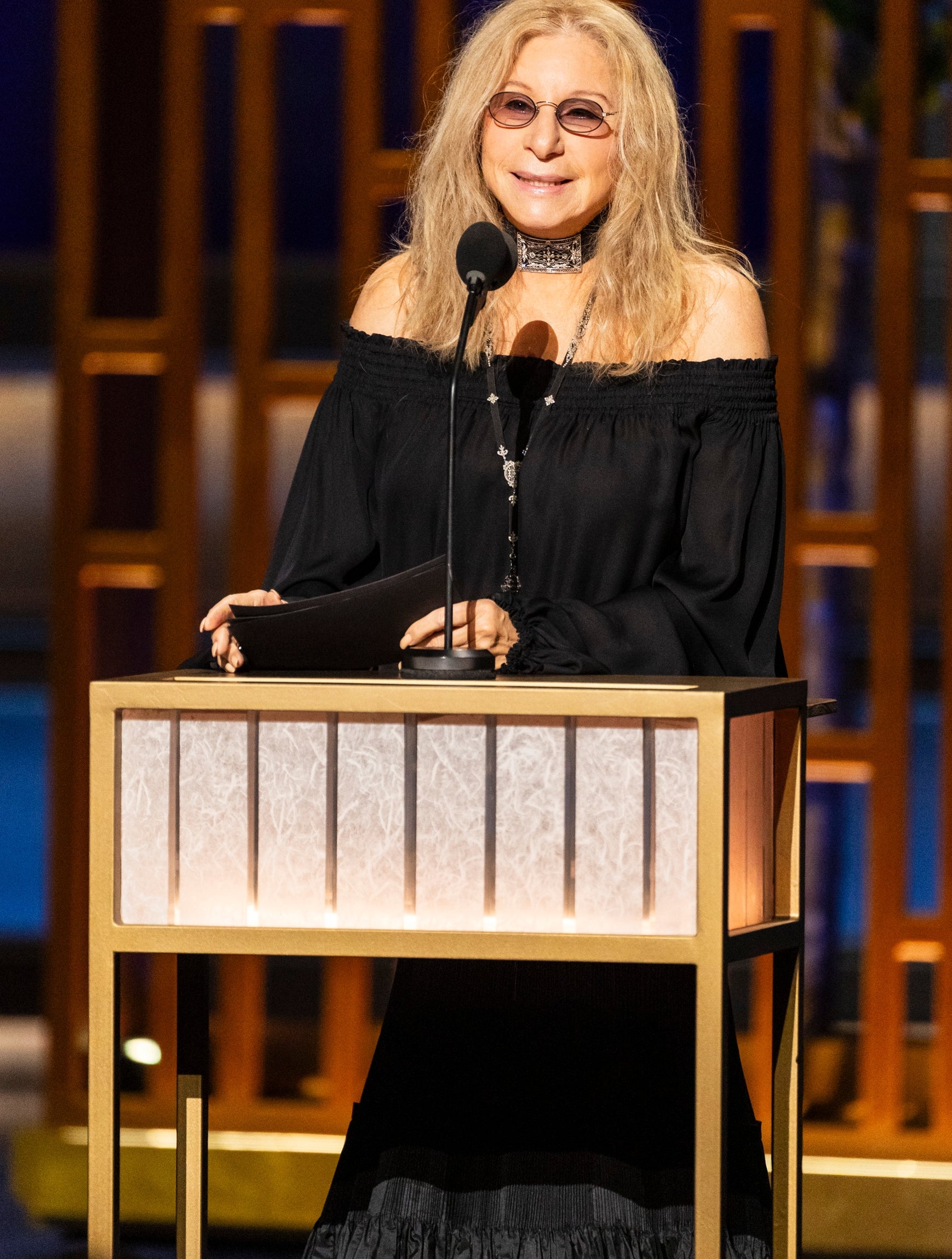 Barbra Streisand lasting  astatine  a podium, speaking into a microphone during an event