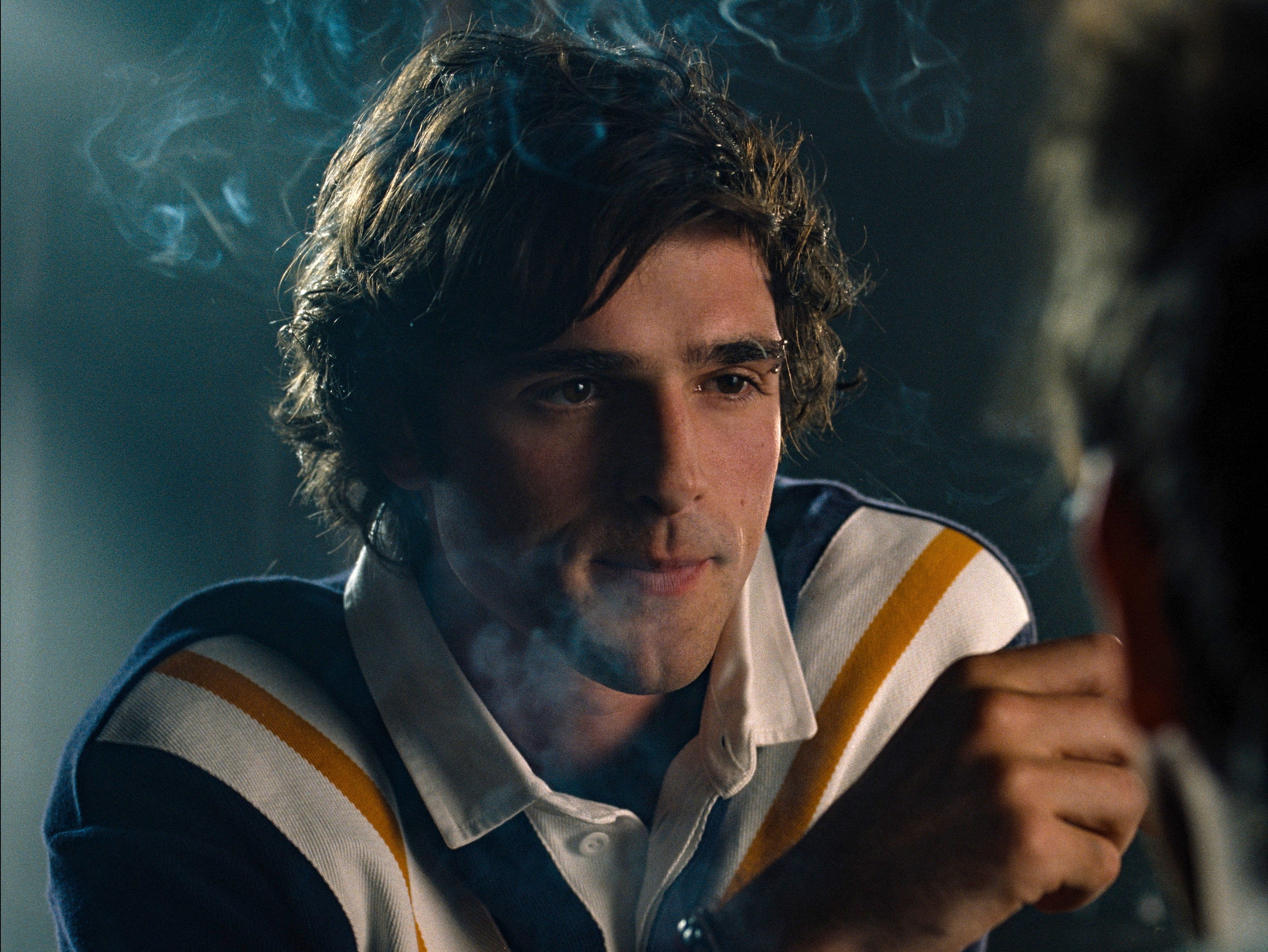 Person with wavy hairsbreadth successful a striped sweater, surrounded by smoke, successful a contemplative setting