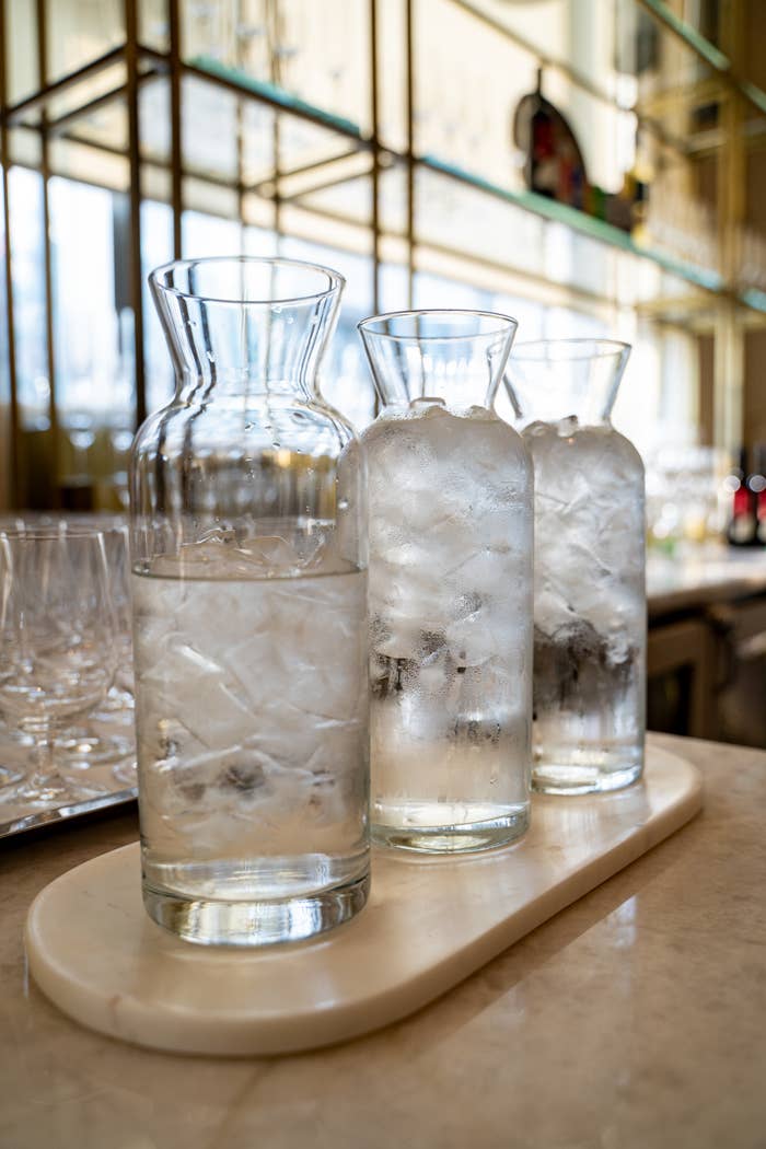 Three solid  pitchers filled with crystal  h2o  connected  a tray successful  a modern   barroom  setting