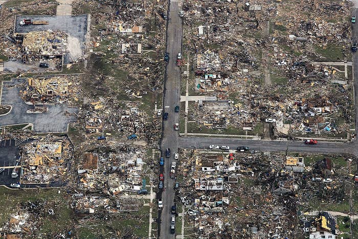 Aerial presumption    of a vicinity  devastated by a tornado, showing destroyed homes, debris scattered everywhere, and immoderate   cars connected  the street