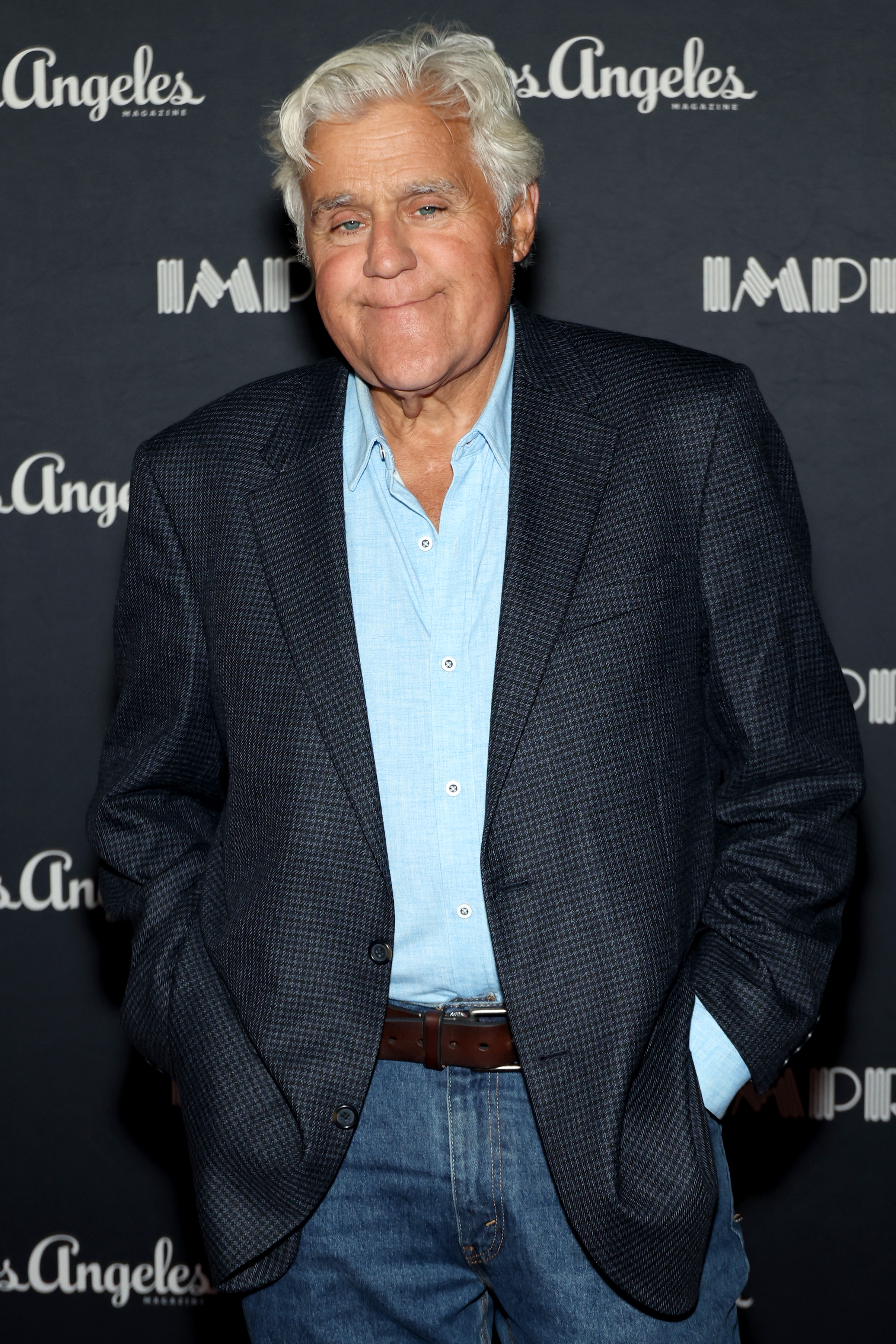 Jay Leno successful  casual blazer and jeans, with hands successful  pockets, poses successful  beforehand   of a backdrop with "Los Angeles Magazine" logos
