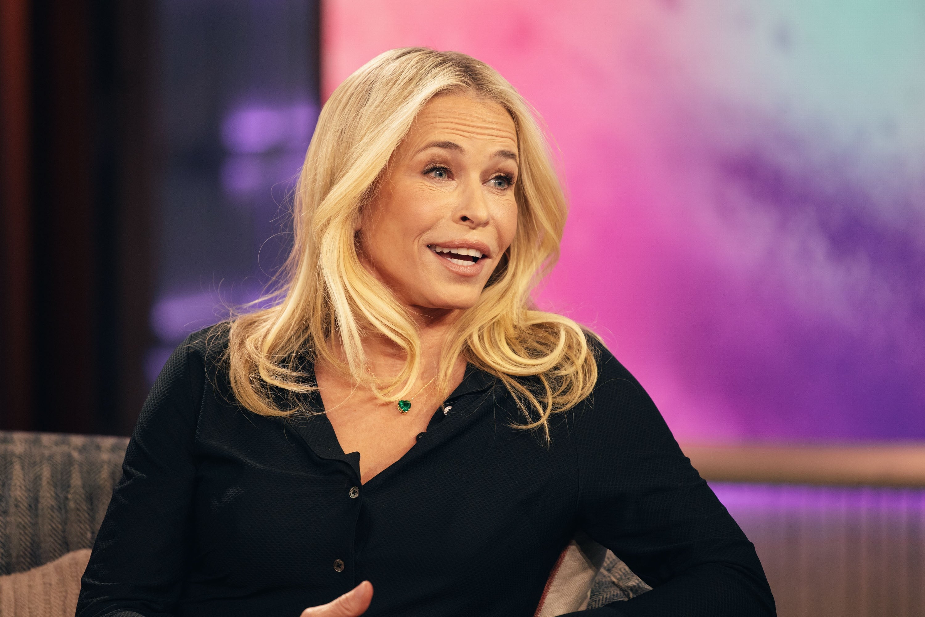 En person med langt blondt hår, i en svart topp, sitter på en sofa og snakker under et intervju