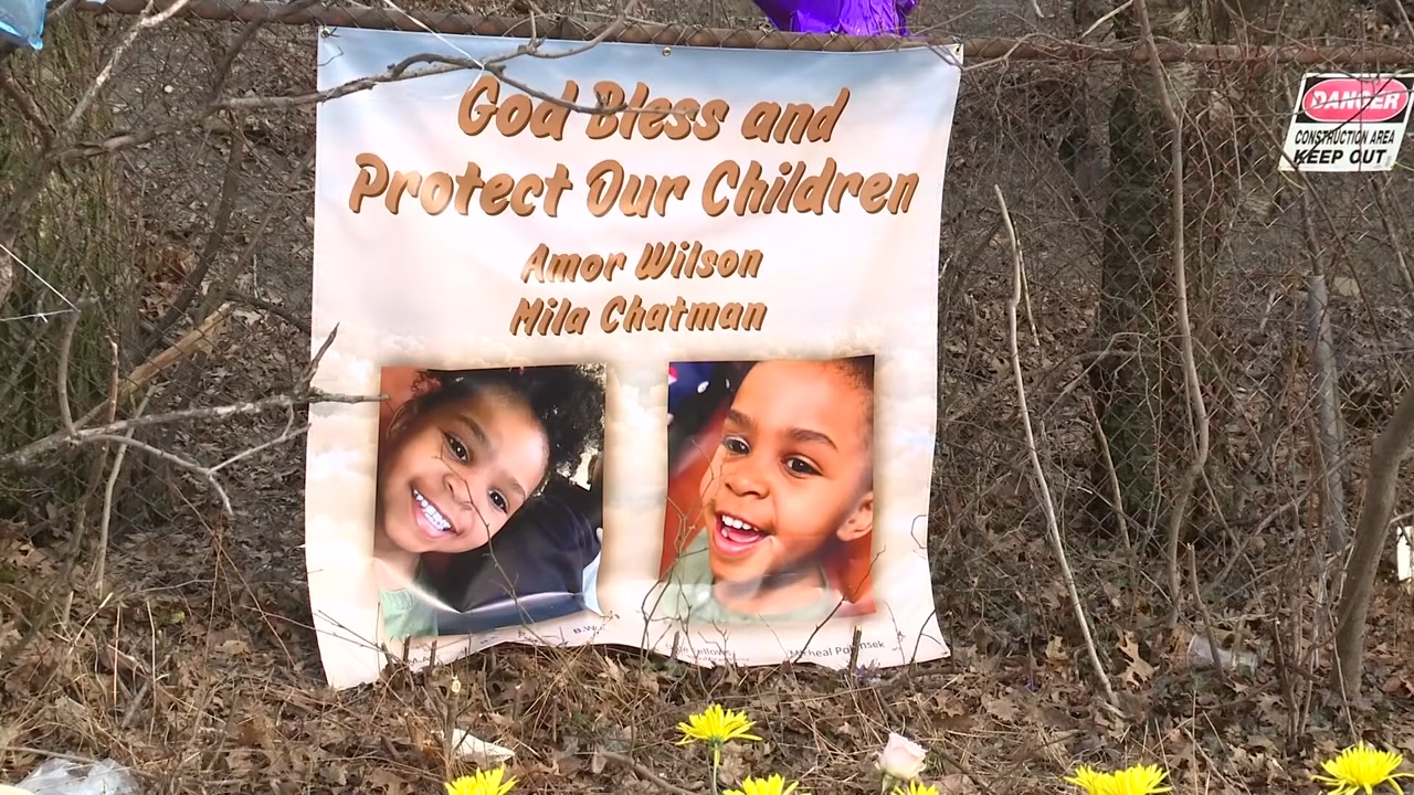Memorial banner connected a obstruction with "God Bless and Protect Our Children" featuring photos of 2 smiling children