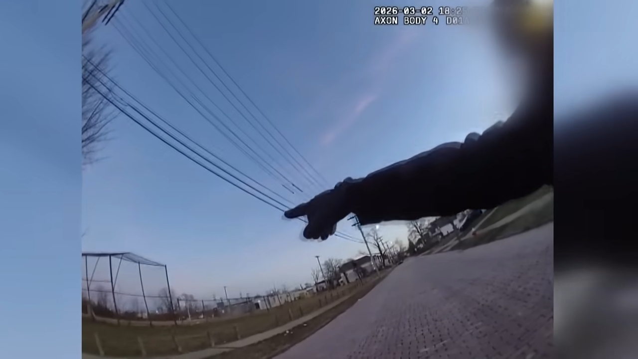 A assemblage cam shows an officer's limb pointing down a thoroughfare with powerfulness lines overhead, successful a vicinity setting