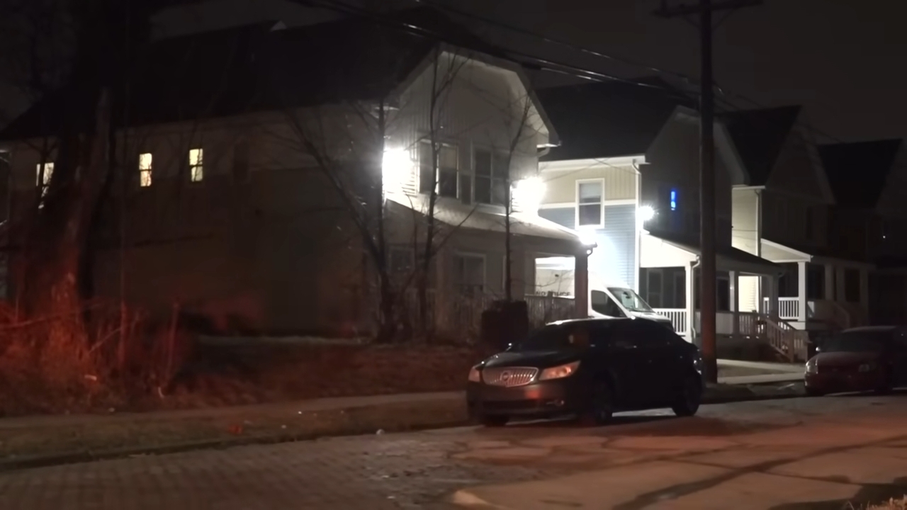 A dimly lit residential thoroughfare astatine night, featuring a parked car successful beforehand of houses with illuminated windows