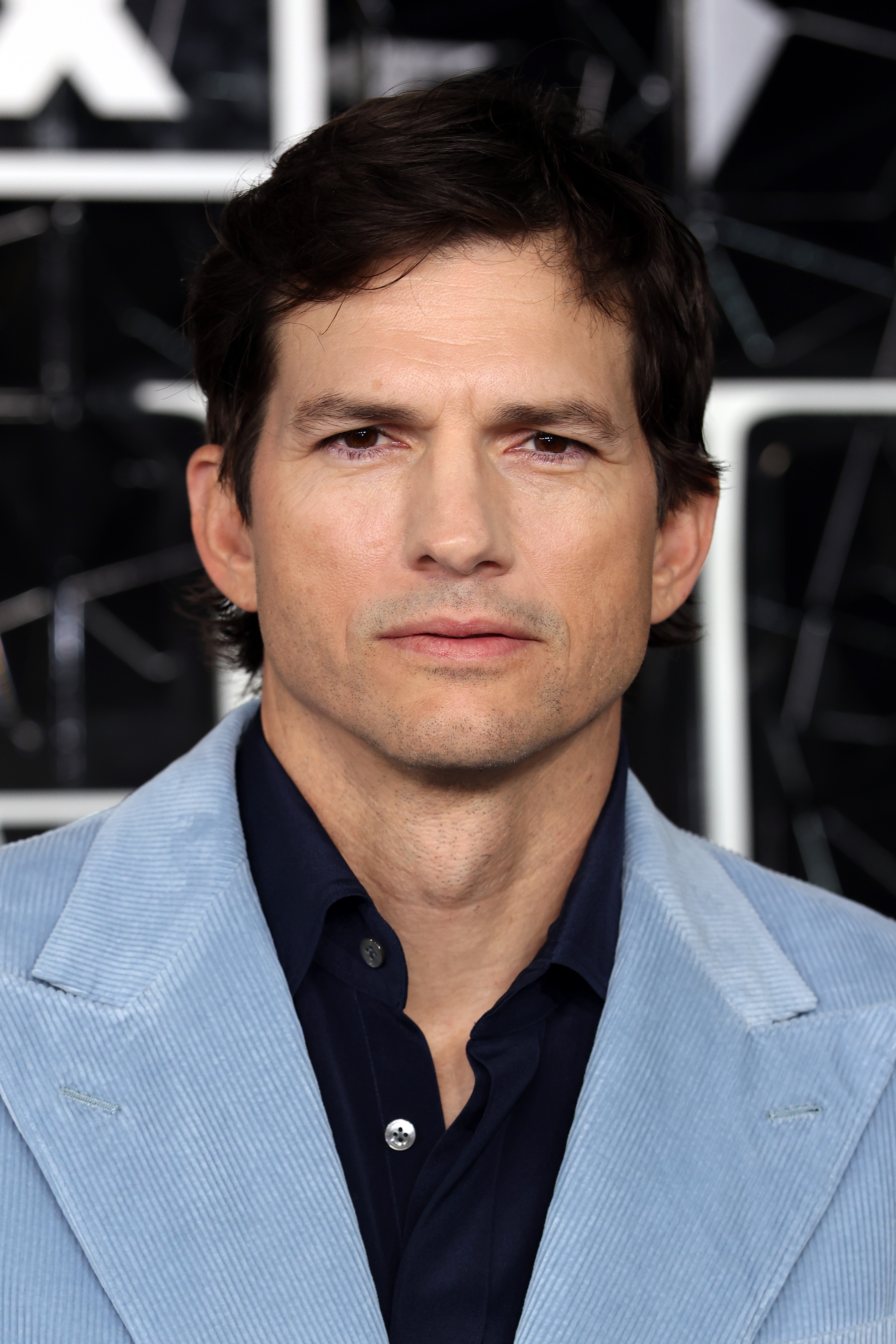 Ashton Kutcher successful  a stylish bluish  blazer and acheronian  garment  poses astatine  a personage  event