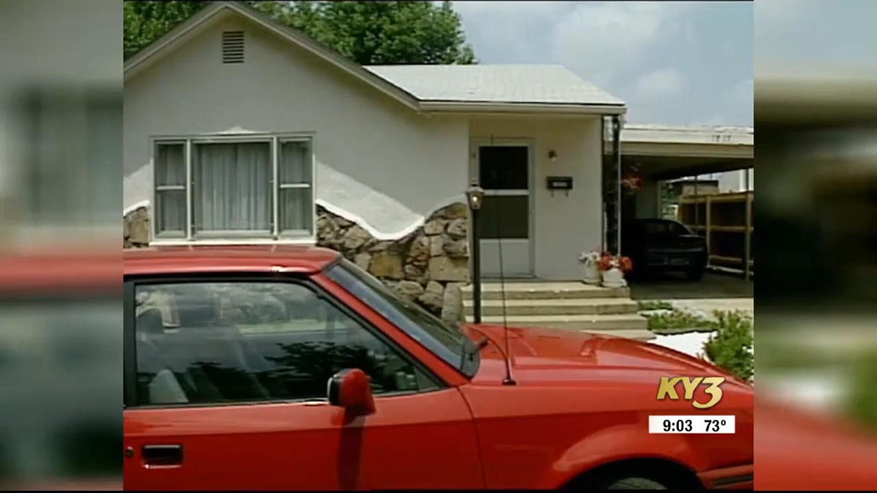 A reddish car parked successful beforehand of a tiny location with a chromatic facade and a covered carport. Sky partially cloudy