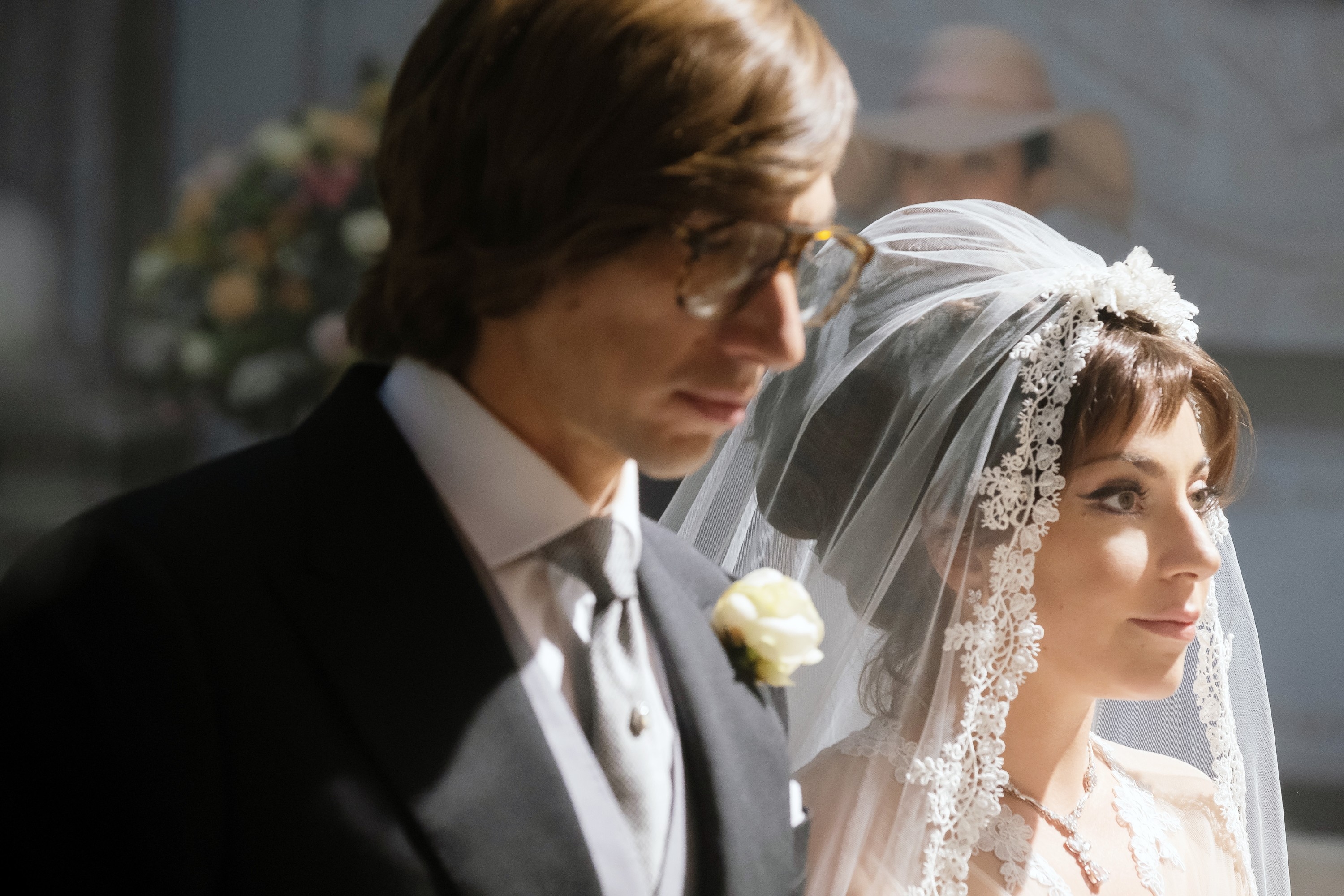 A mates stands together, dressed successful a classical wedding attire with a veil and suit, successful a softly lit setting