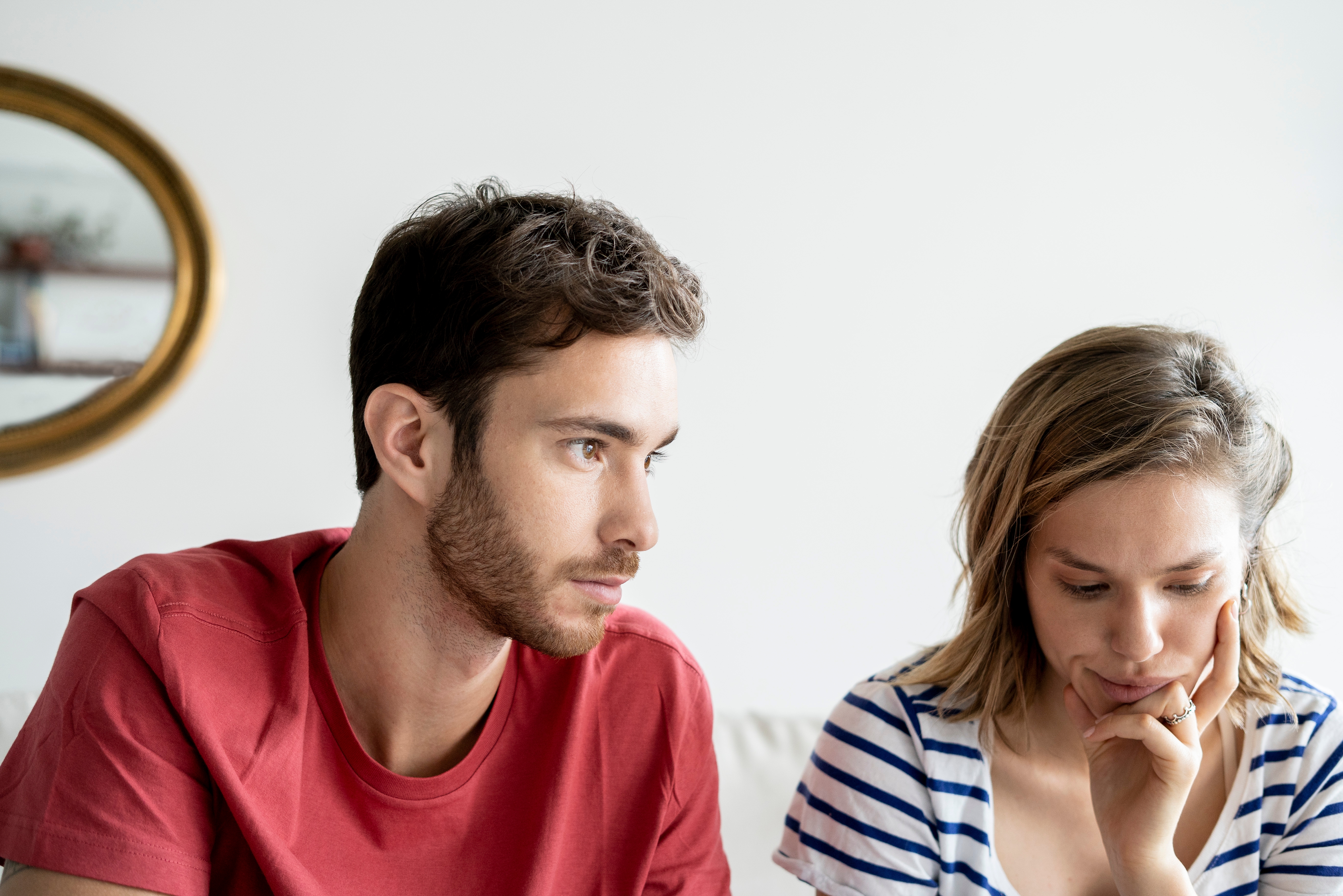 A thoughtful couple sits close together; the woman appears contemplative while the man looks ahead, both reflecting a serious conversation