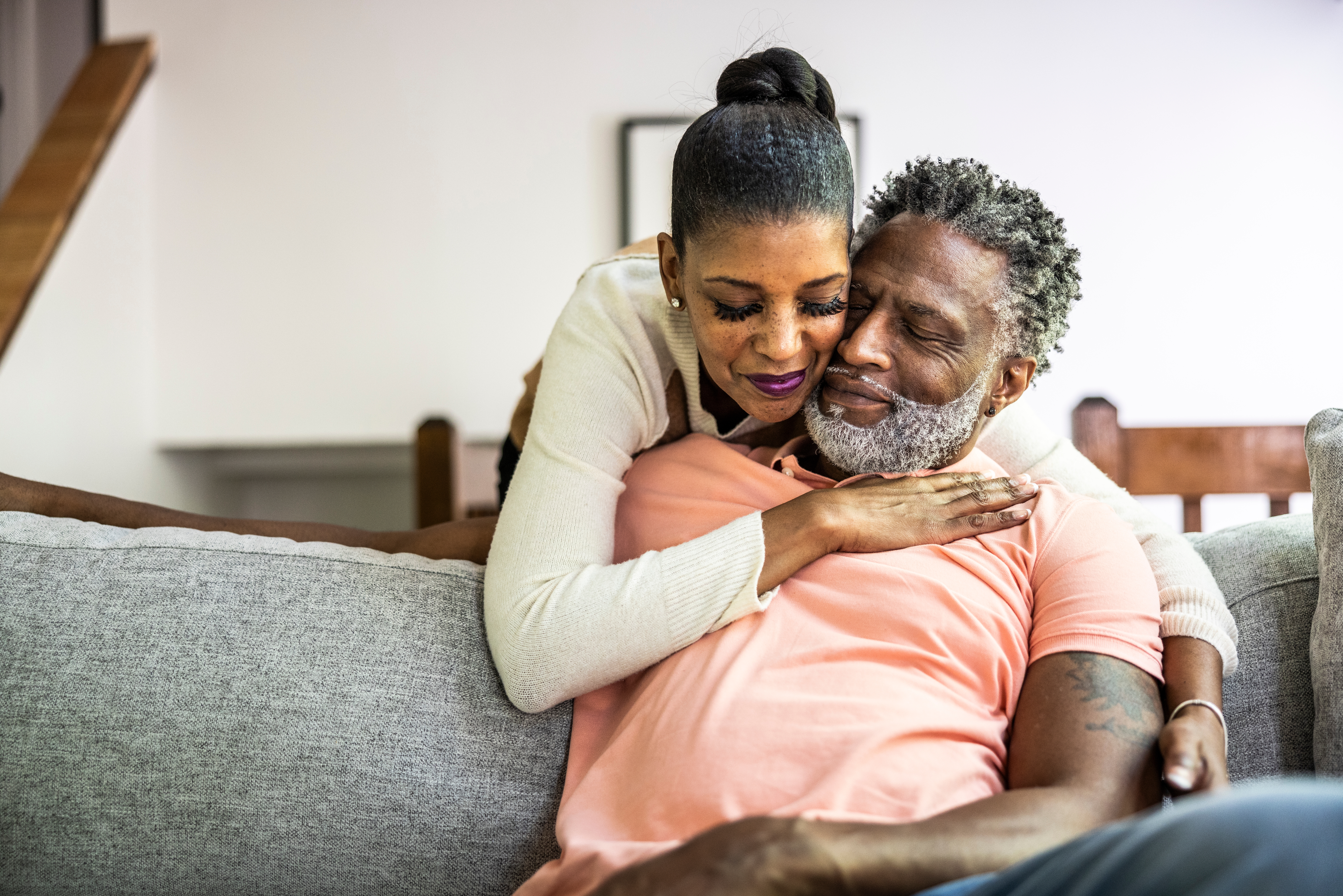 Couple embracing affectionately on a sofa, expressing love and comfort