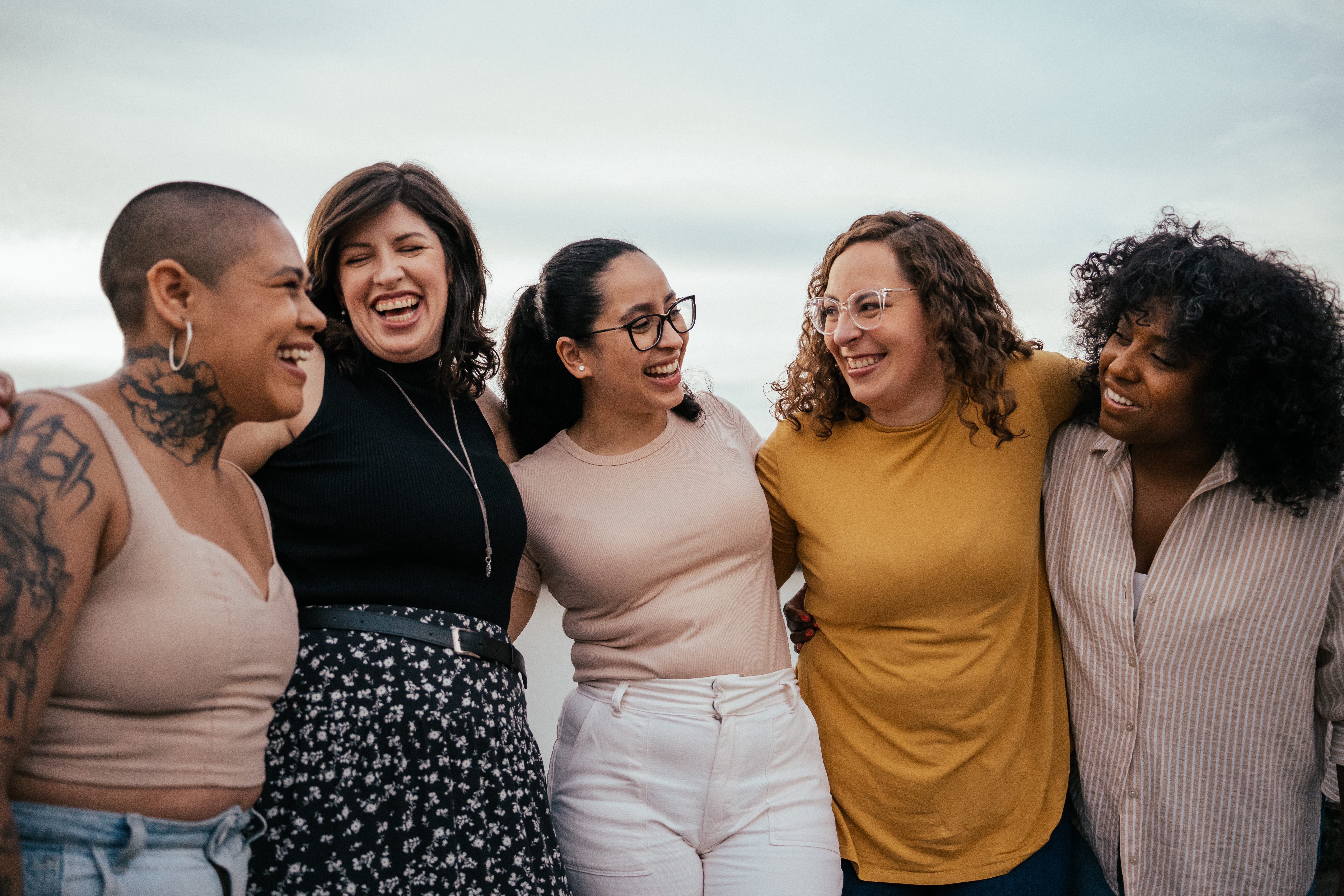 Group of five friends smiling and embracing outside, embodying friendship and joy