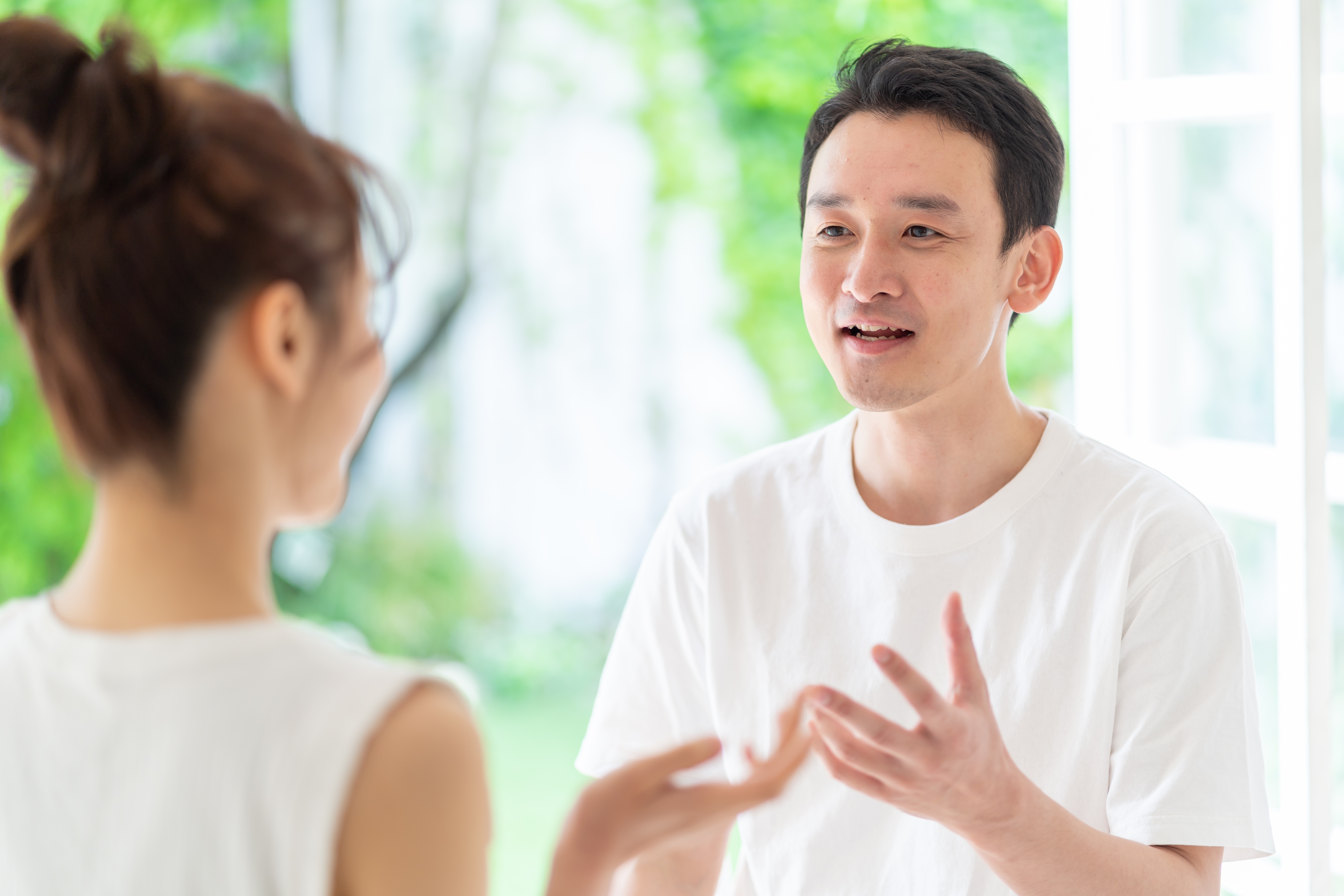 Two people in a lively conversation indoors, both wearing casual white shirts