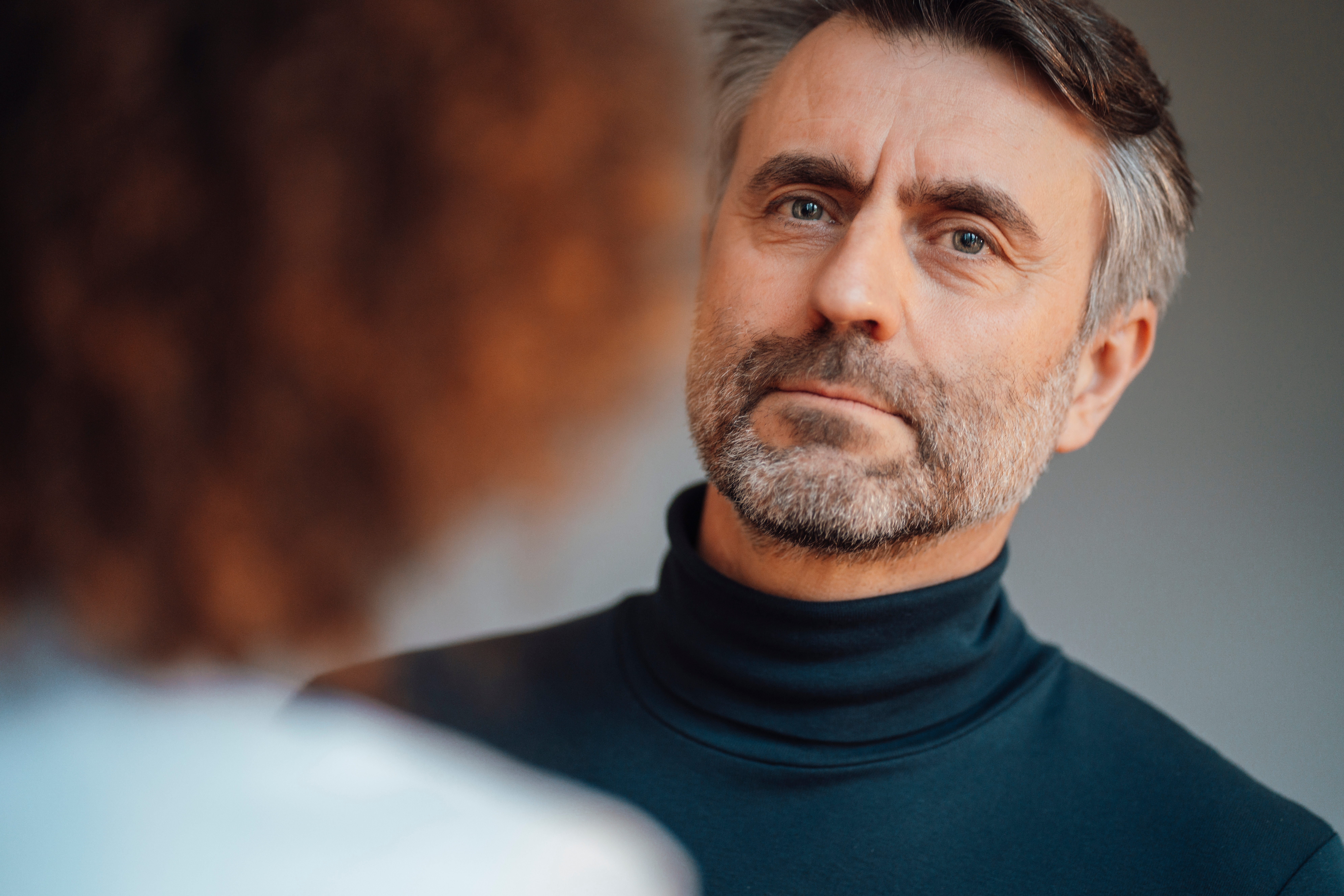 A person in a turtleneck listens intently to another in a thoughtful interaction