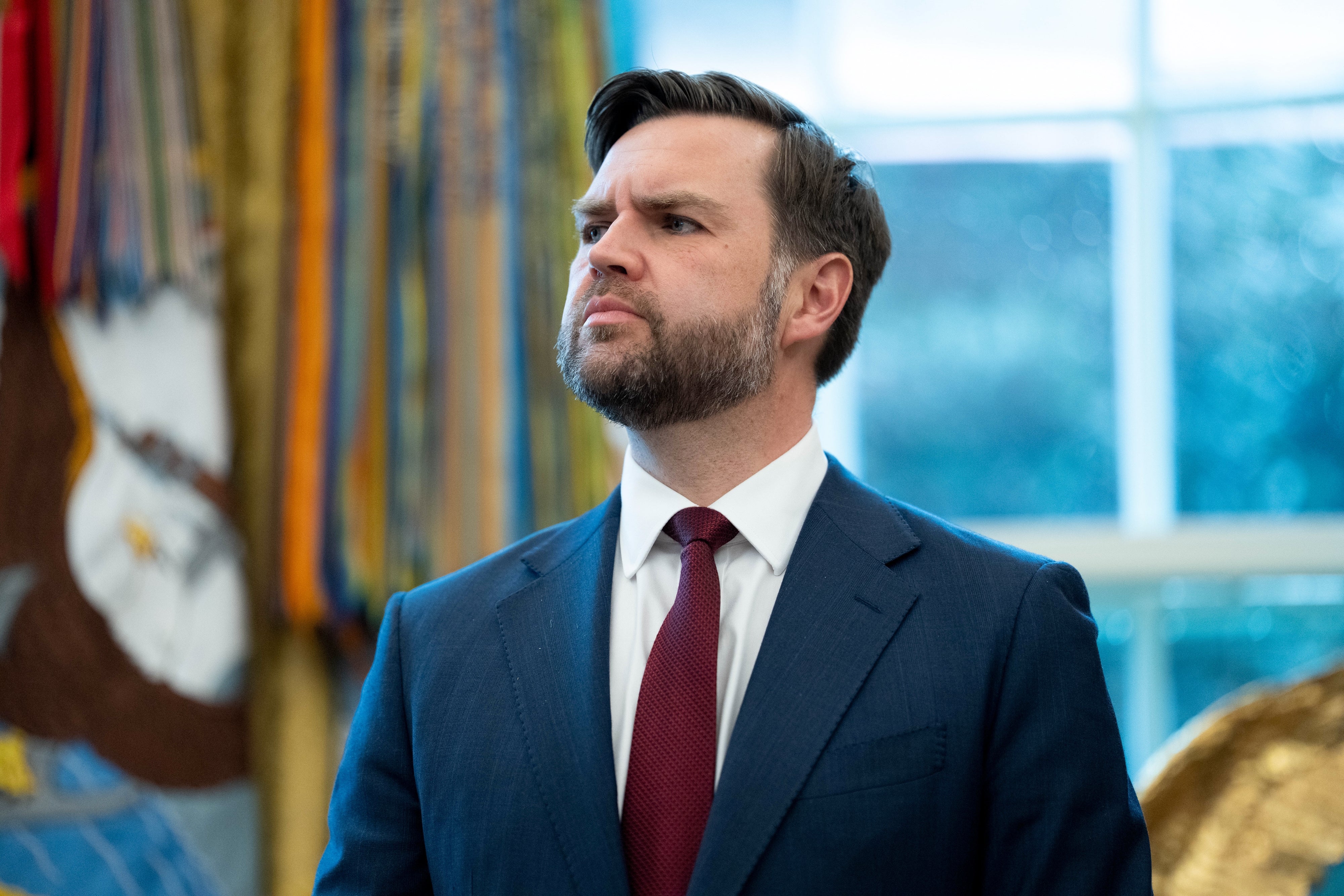 En person i dress og slips står selvsikkert i en innendørs setting med et seriøst uttrykk