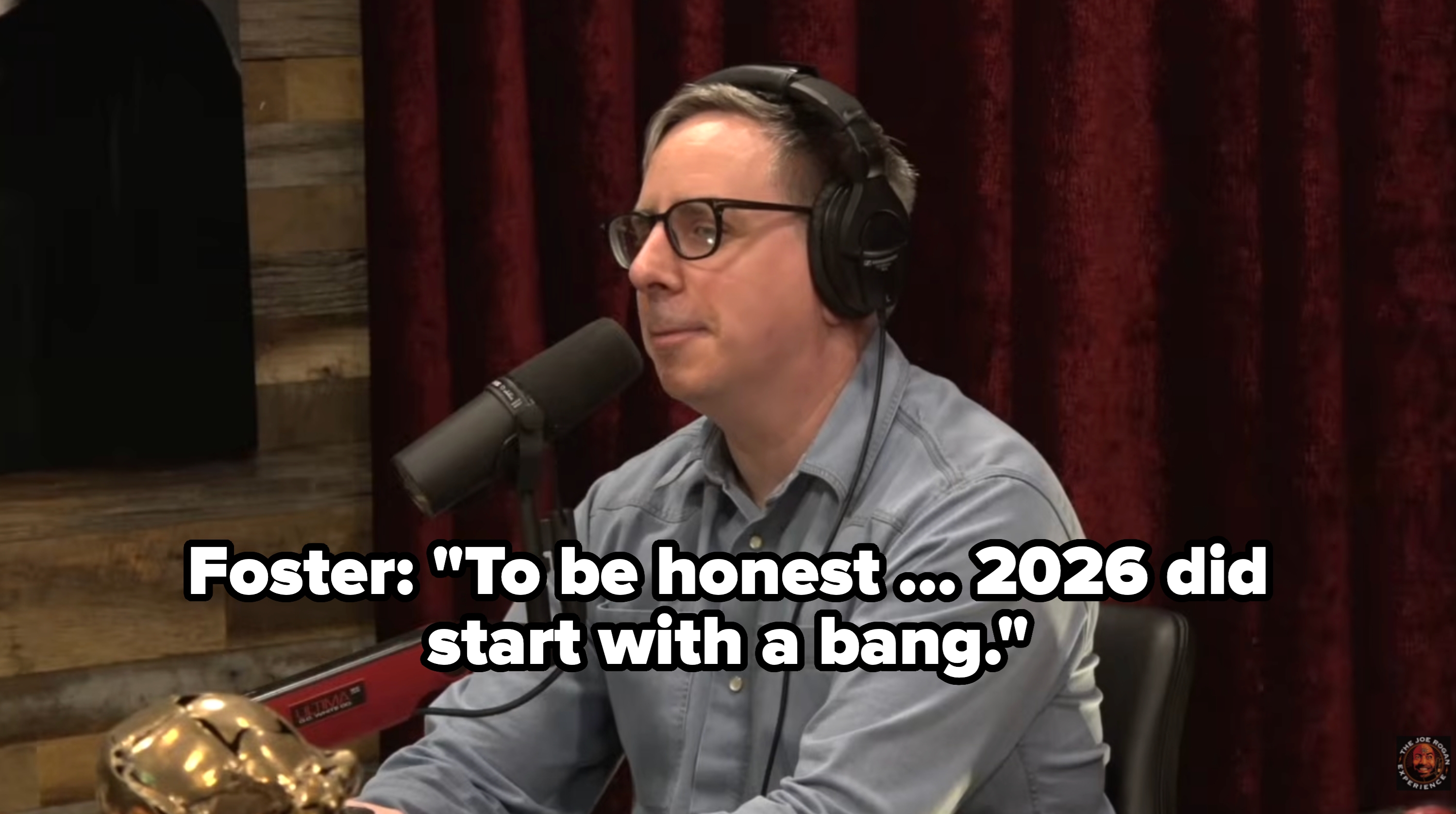 Person with glasses wearing headphones, speaking into a microphone connected  a podcast acceptable   with wood   paneling and acheronian  curtains successful  the background