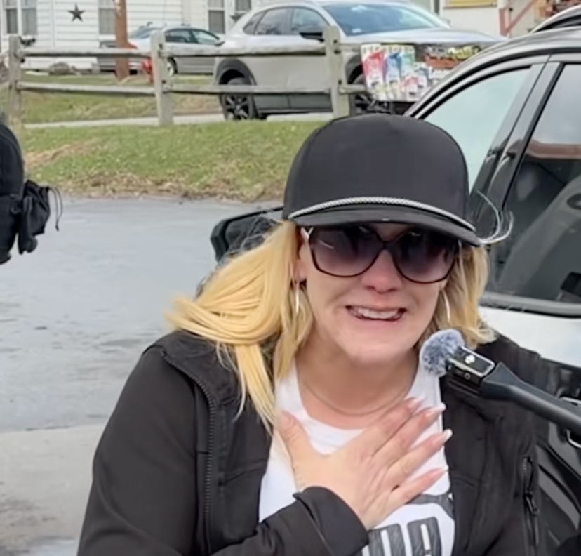 Person lasting  extracurricular  looking emotional, wearing sunglasses and a cap, holding a microphone adjacent   their mouth