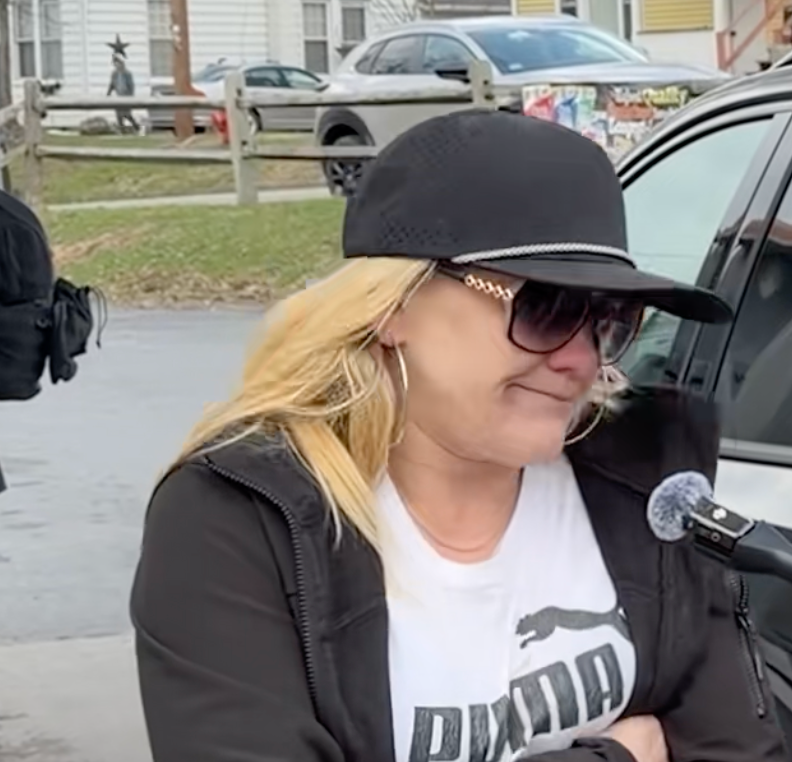 Person successful  casual attire and sunglasses speaking into a microphone outdoors