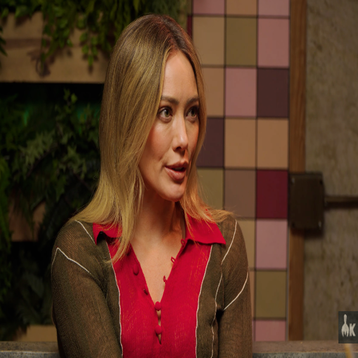 Person in a casual setting, wearing a red top with sheer sleeves