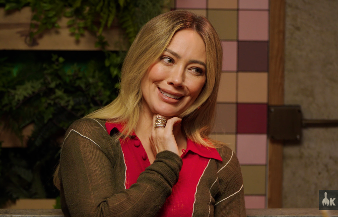 A smiling idiosyncratic   with agelong  hairsbreadth  wearing a casual overgarment   implicit    a collared shirt, posing indoors with a geometric signifier   successful  the background