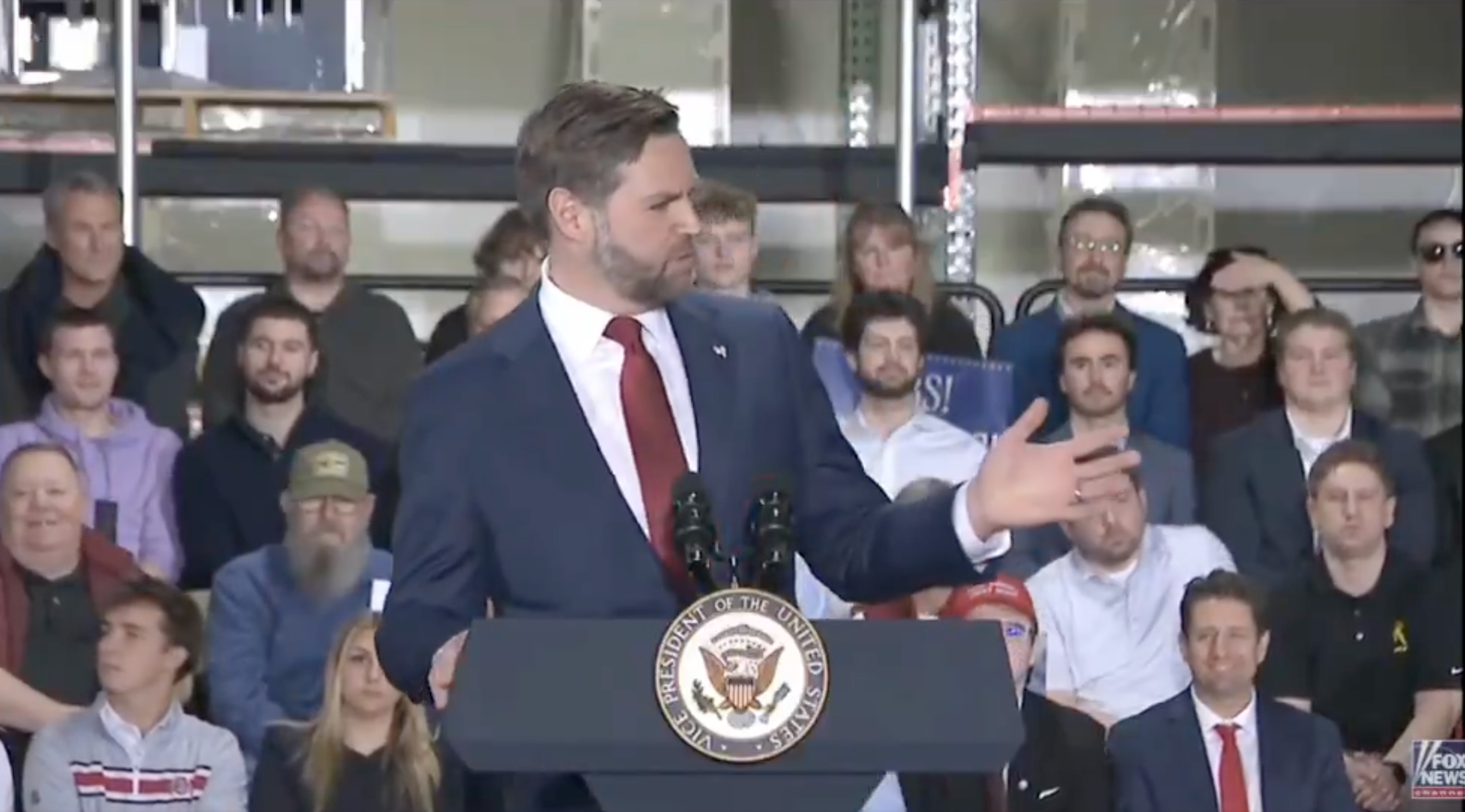 Person successful  a suit   speaking astatine  a podium with a US emblem, facing an audience