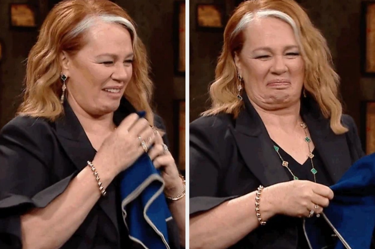 Person reacting humorously and folding a napkin, wearing a blazer and jewelry