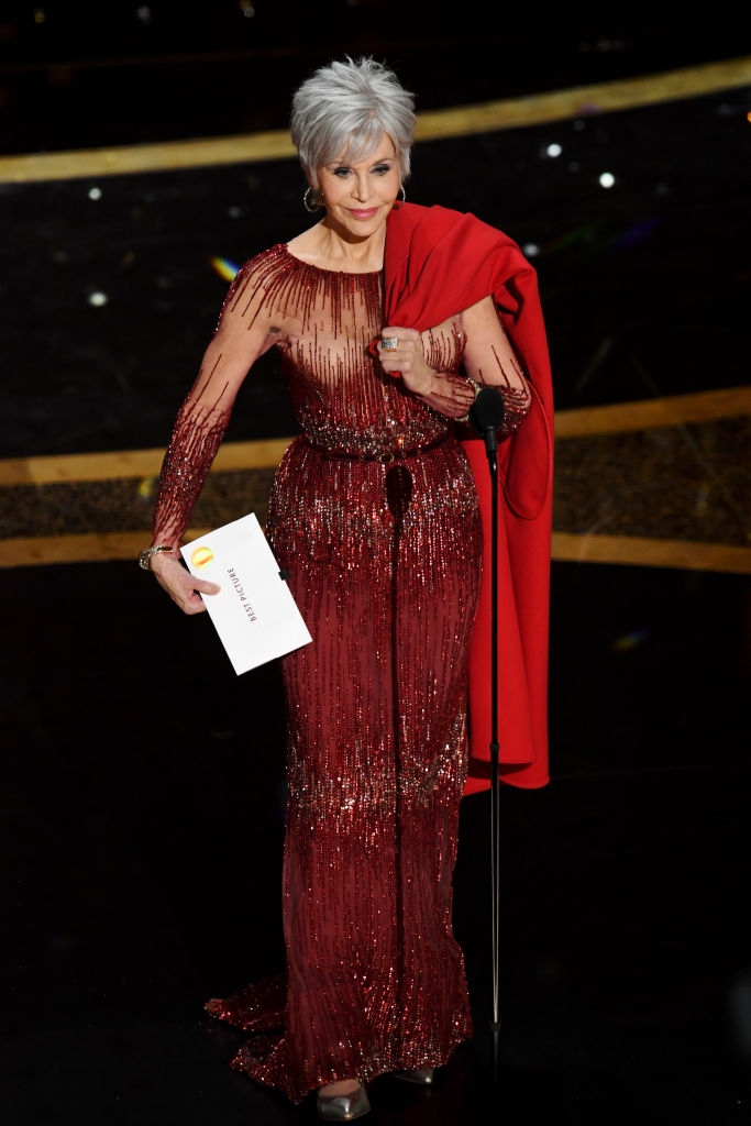 Jane successful  an elegant, shimmering gown with a matching coat, holding an envelope connected  stage