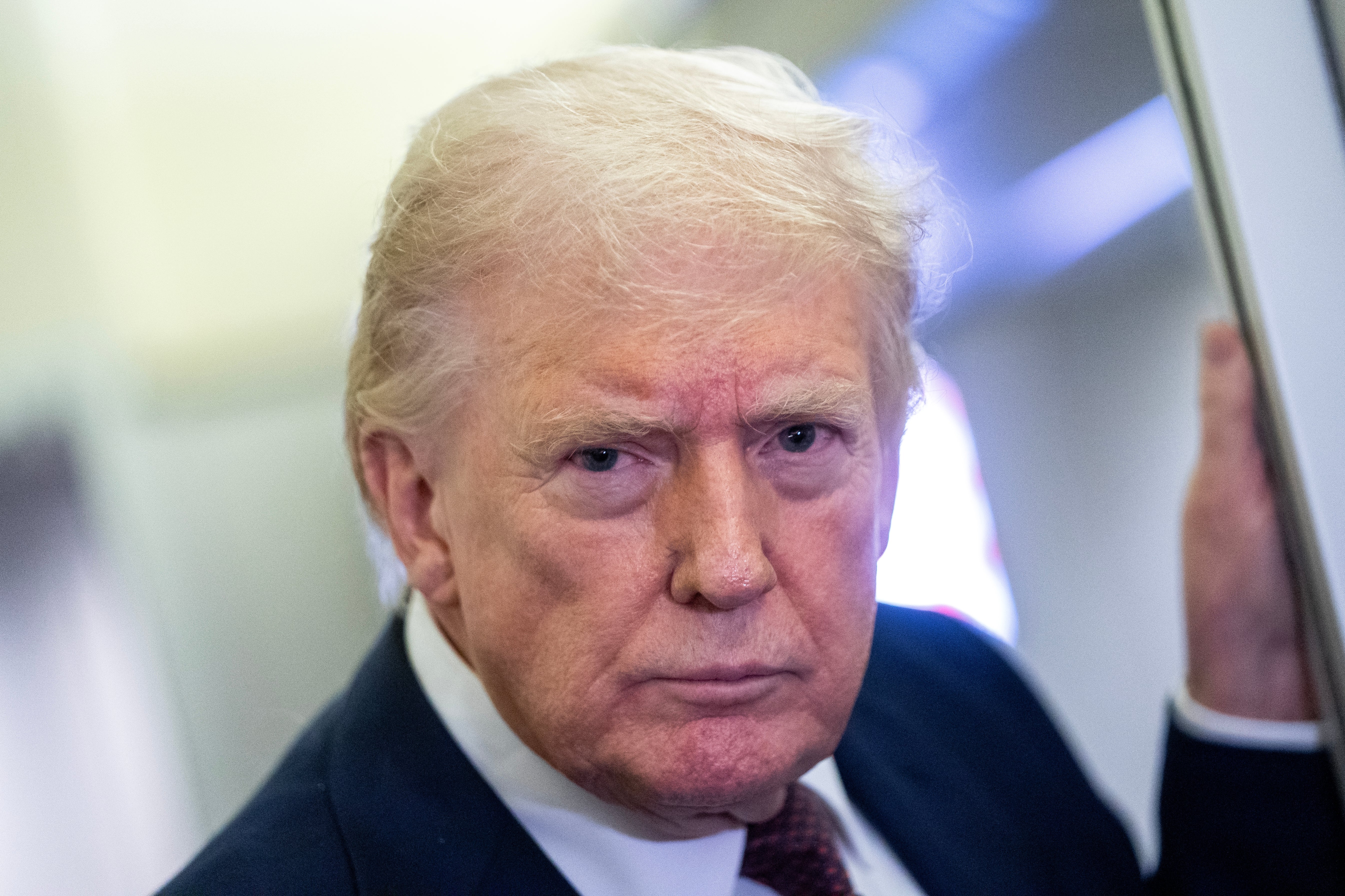 En person med et alvorlig uttrykk, iført en dress, ser direkte på kameraet i et nærbilde