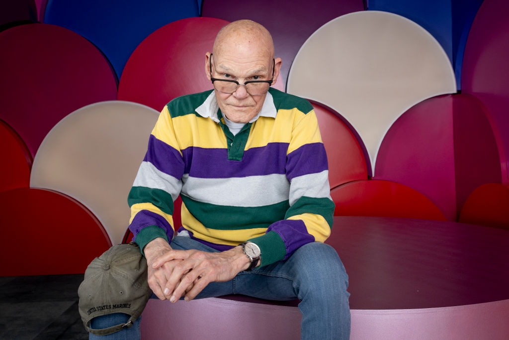 Person wearing a striped rugby garment  and glasses sits successful  beforehand   of a colorful backdrop