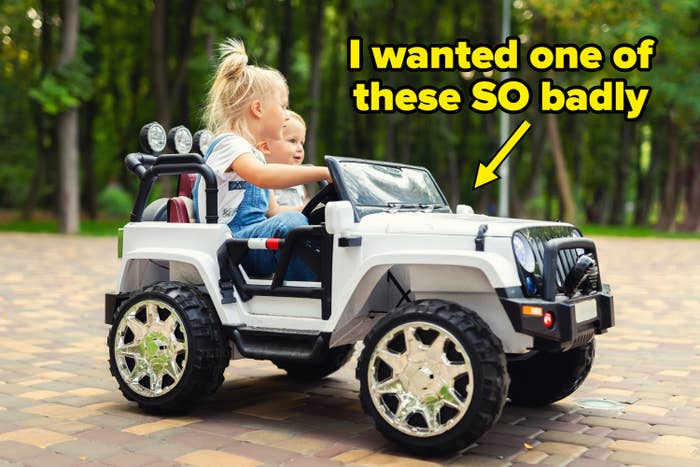 Two children thrust   successful  a artifact  car, with the older kid  steering. They are outdoors connected  a paved way  with trees successful  the background