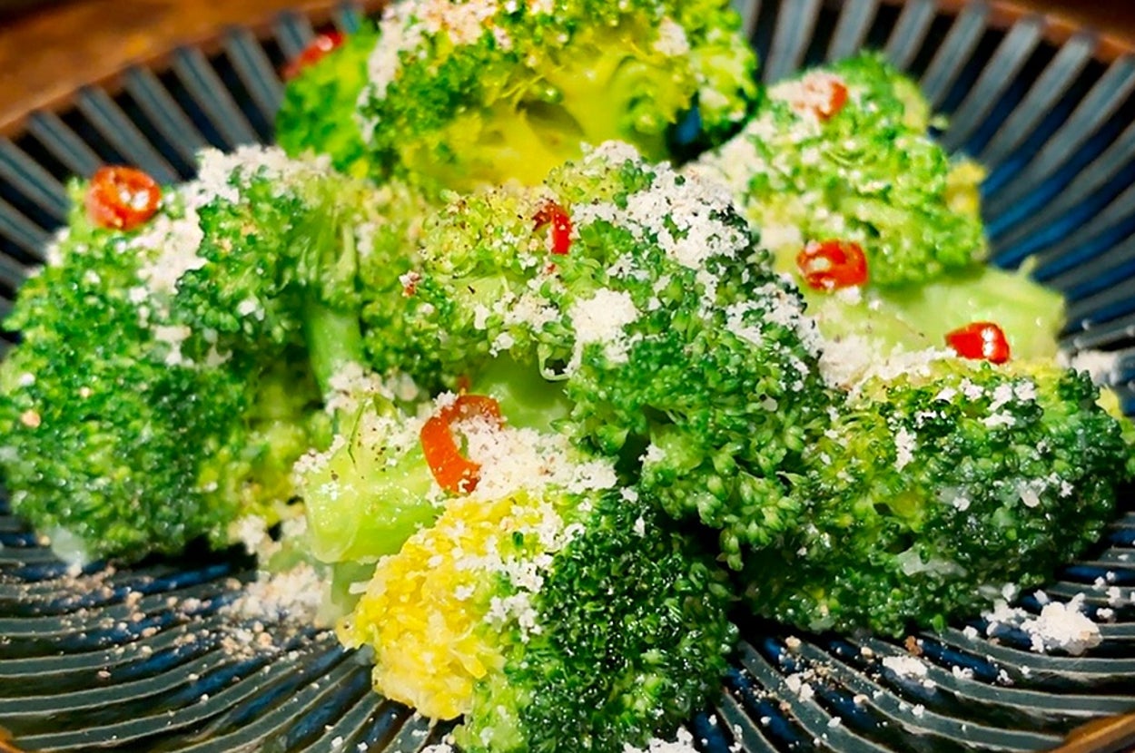 皿に盛られたブロッコリーに、チーズと赤唐辛子がふりかけられている。