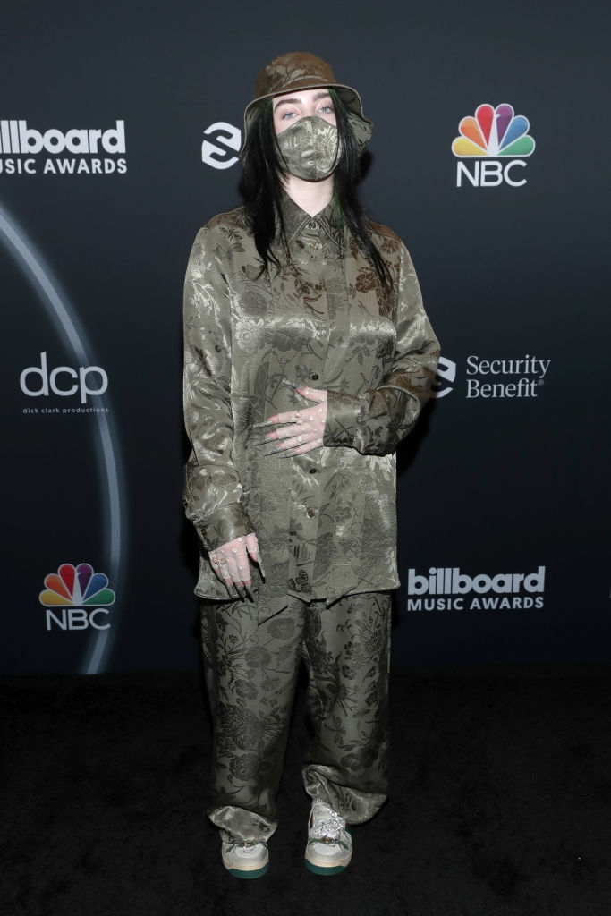 Billie connected  the reddish  carpet wears a floral-patterned bucket hat, mask, and escaped   clothing