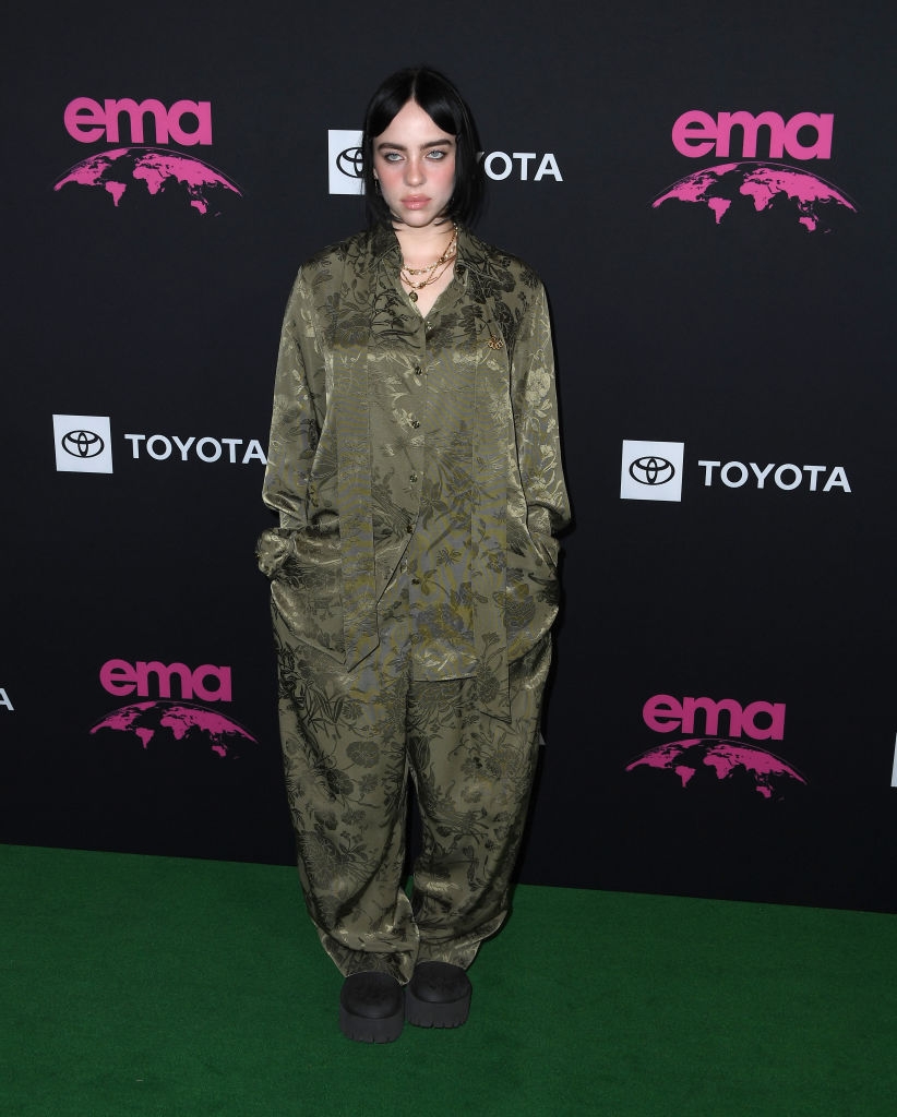 Billie wearing a relaxed-fit, patterned outfit with a floral plan  and layered necklaces